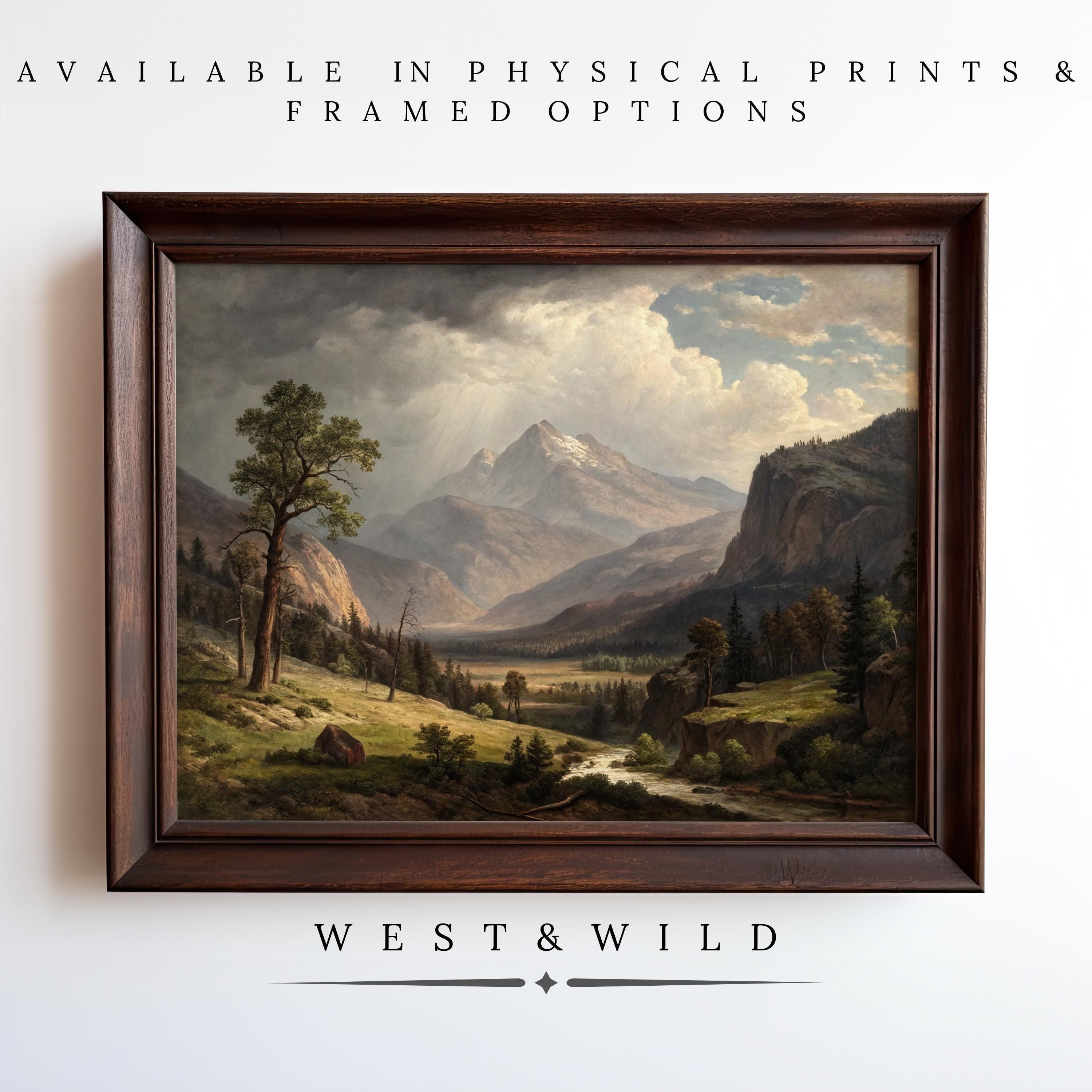 The Mountain Landscape Painting - Moody Oil Painting, ideal for rustic cabin decor, hangs on a white wall. Text above says Available in physical prints & framed options; below, West & Wild.