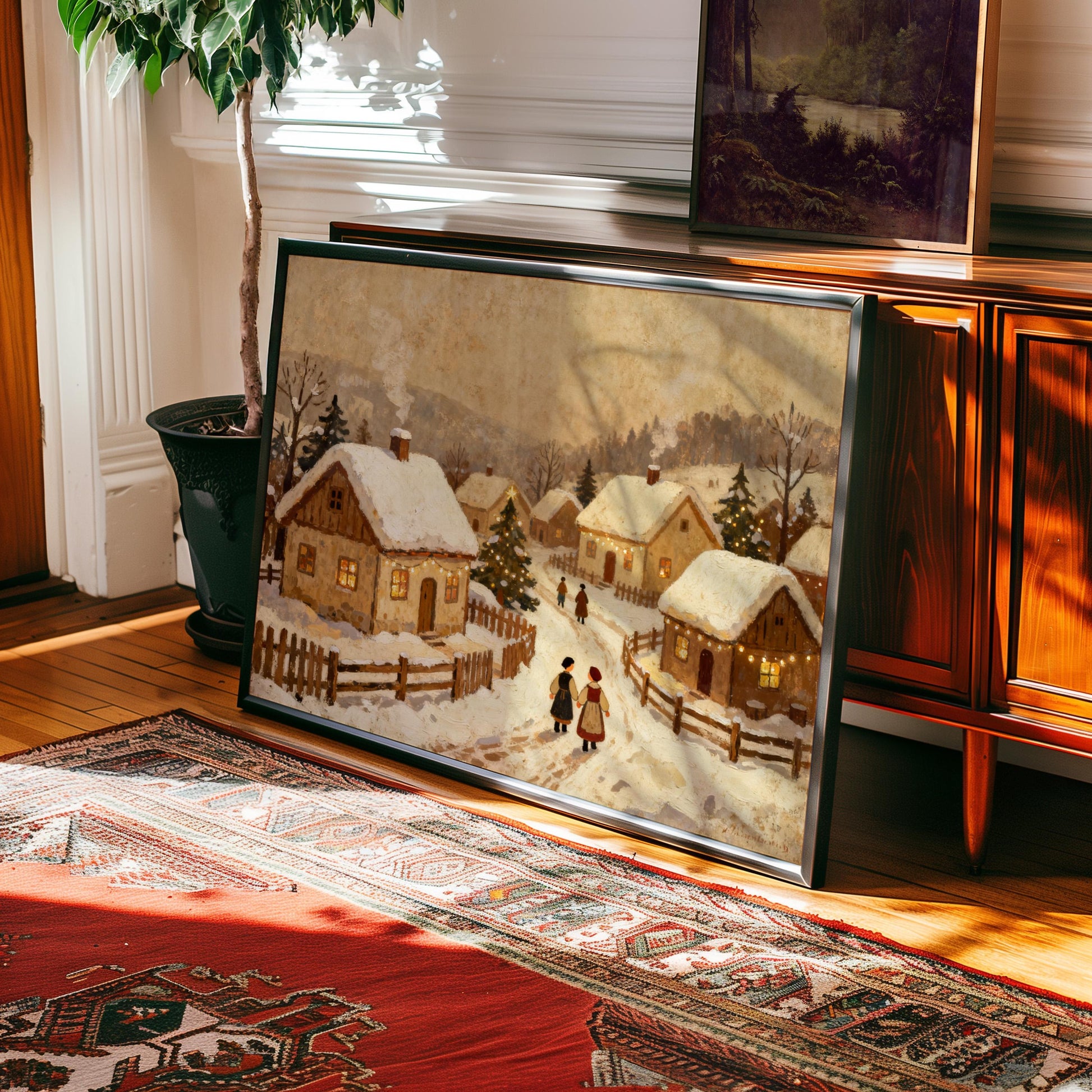 A Vintage Holiday Wall Art – Snowy Village Christmas Print on matte paper with frame options is propped against a wooden cabinet in a sunlit room with a red patterned rug and potted plant.