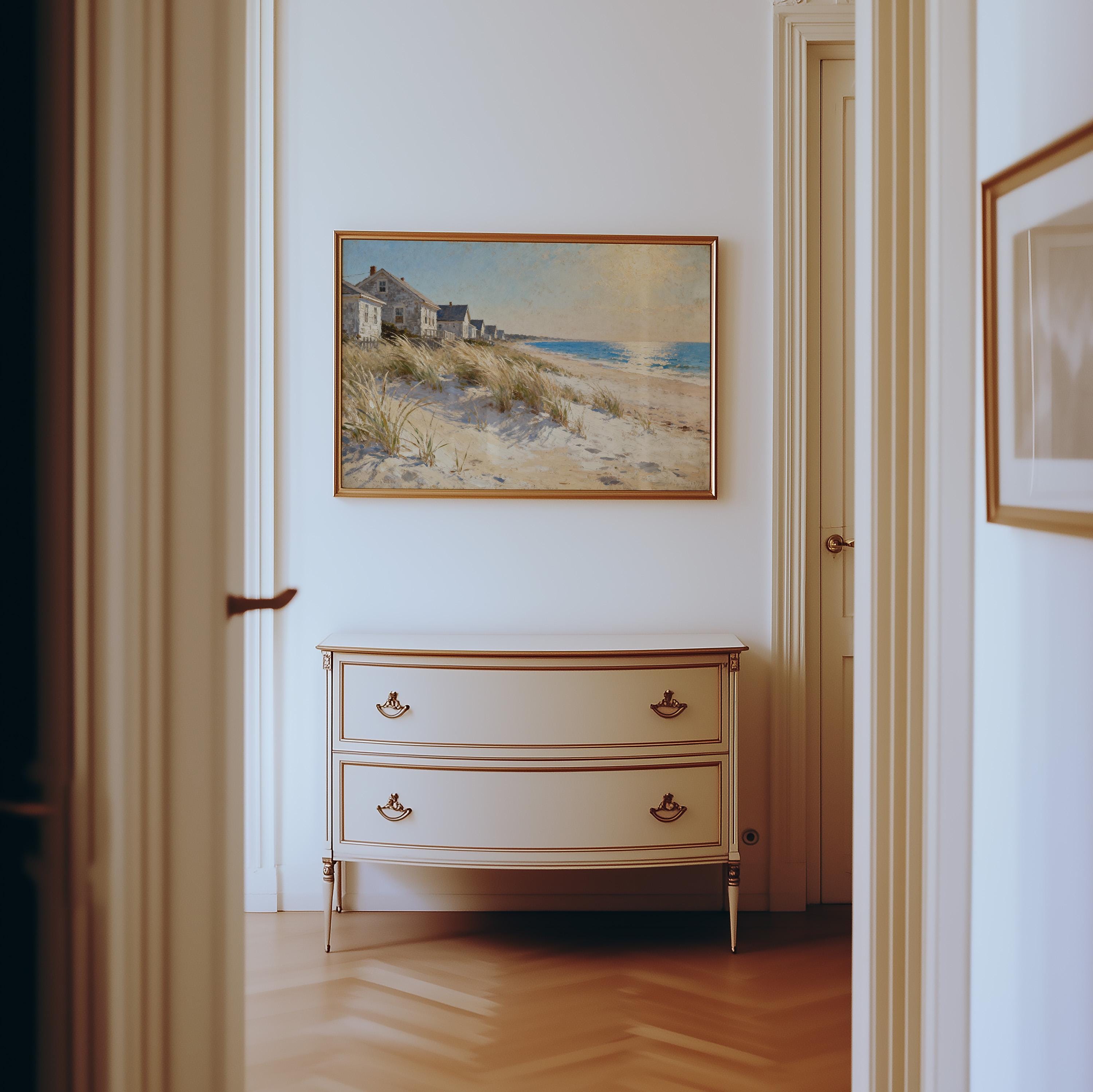 a hallway with a painting of a beach scene hanging on the wall above a white dresser with two drawers.