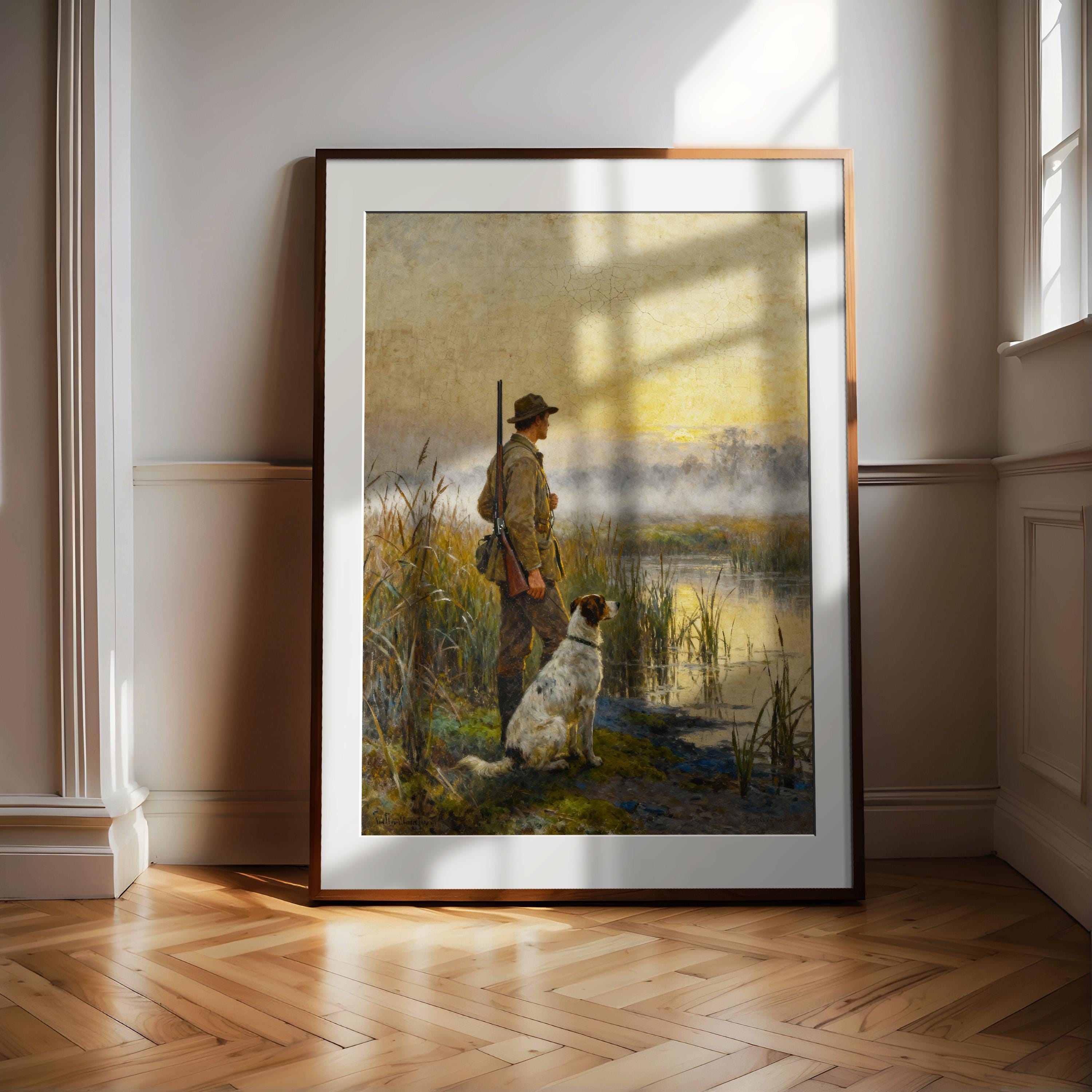 A framed painting depicting a man with a rifle and a dog standing in a grassy field, with a body of water in the background.