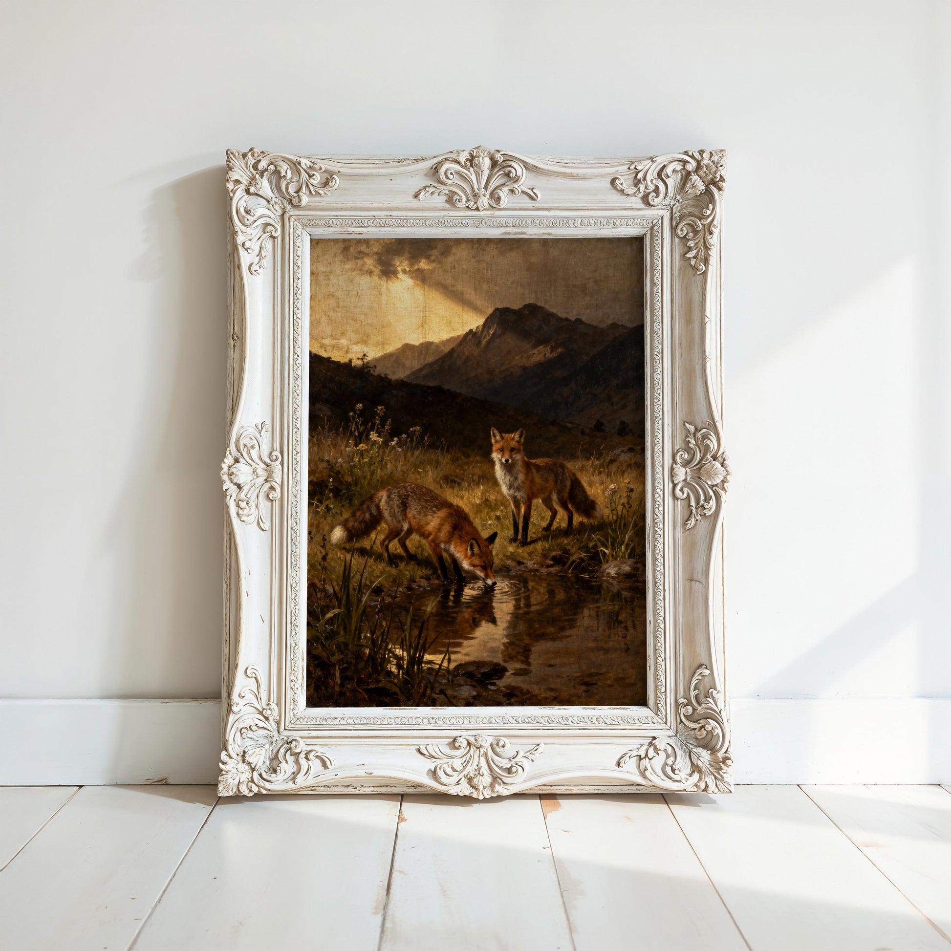 two foxes in a natural setting, with one fox drinking from a stream and the other standing nearby. The foxes are surrounded by lush vegetation, and the scene is framed in an ornate white frame.