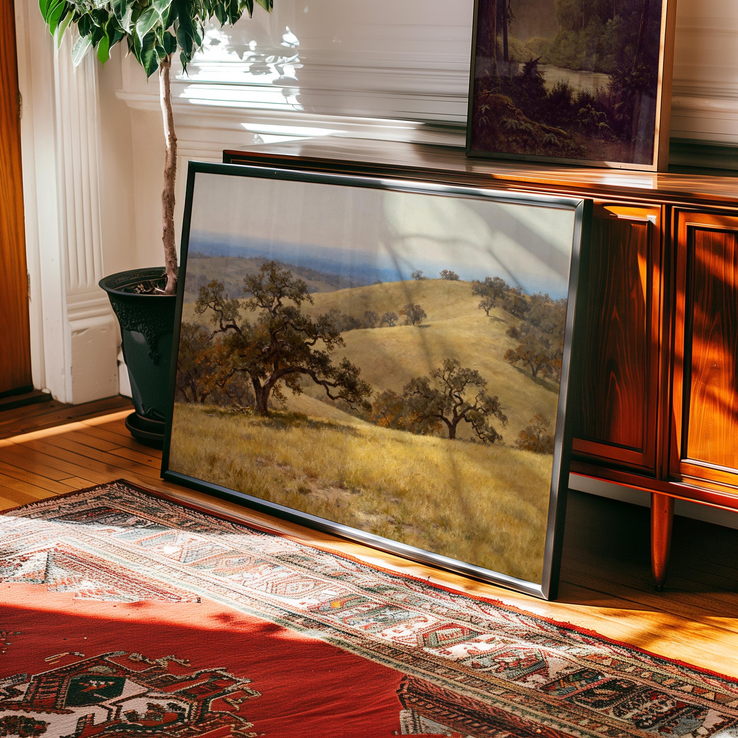 a large framed landscape painting depicting a serene countryside scene with rolling hills and trees.