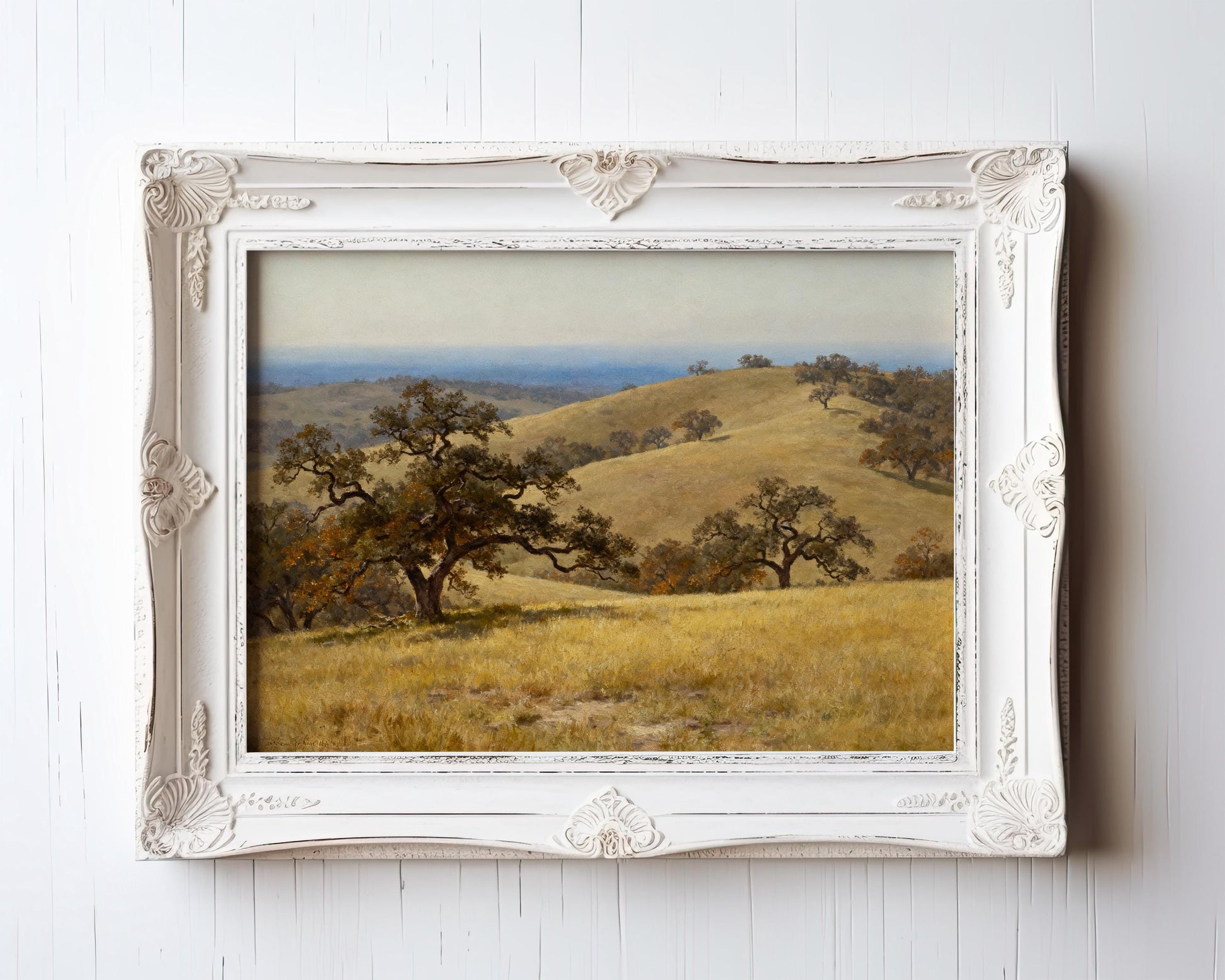 The image is a framed painting depicting a serene landscape with rolling hills, lush trees, and a clear blue sky.