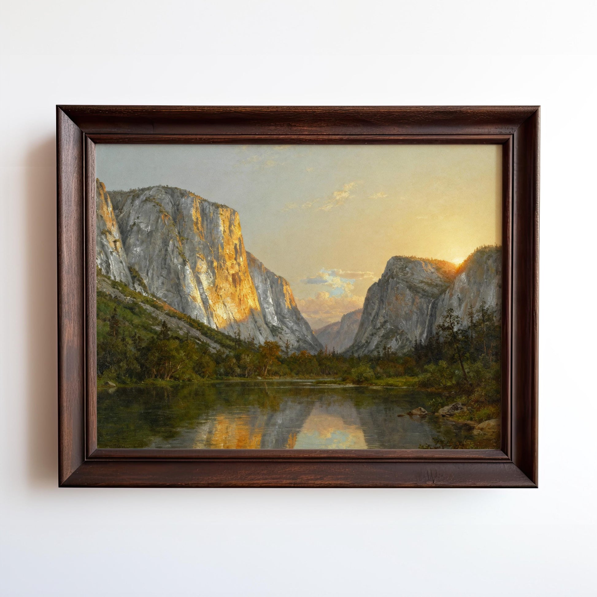 The image is a framed painting depicting a serene landscape with a lake surrounded by towering mountains. The painting showcases the natural beauty of the scene, with the sun setting over the mountains and casting a warm glow on the water.