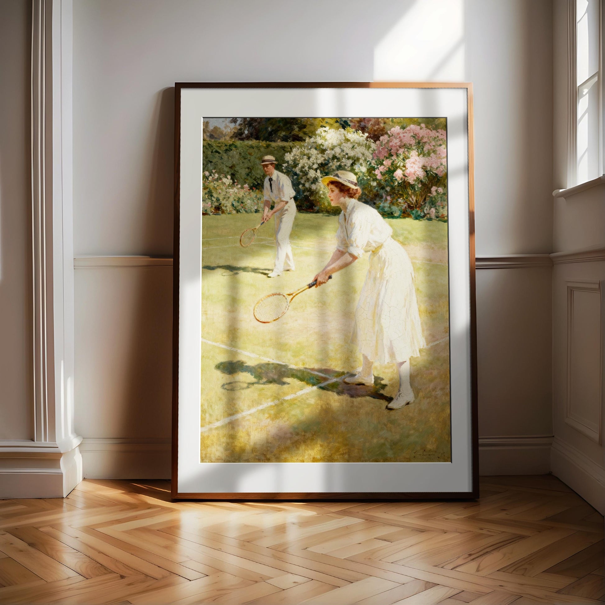 A framed painting depicting a woman in a white dress playing tennis on a grass court, with a man in a hat and white shirt also visible in the background.