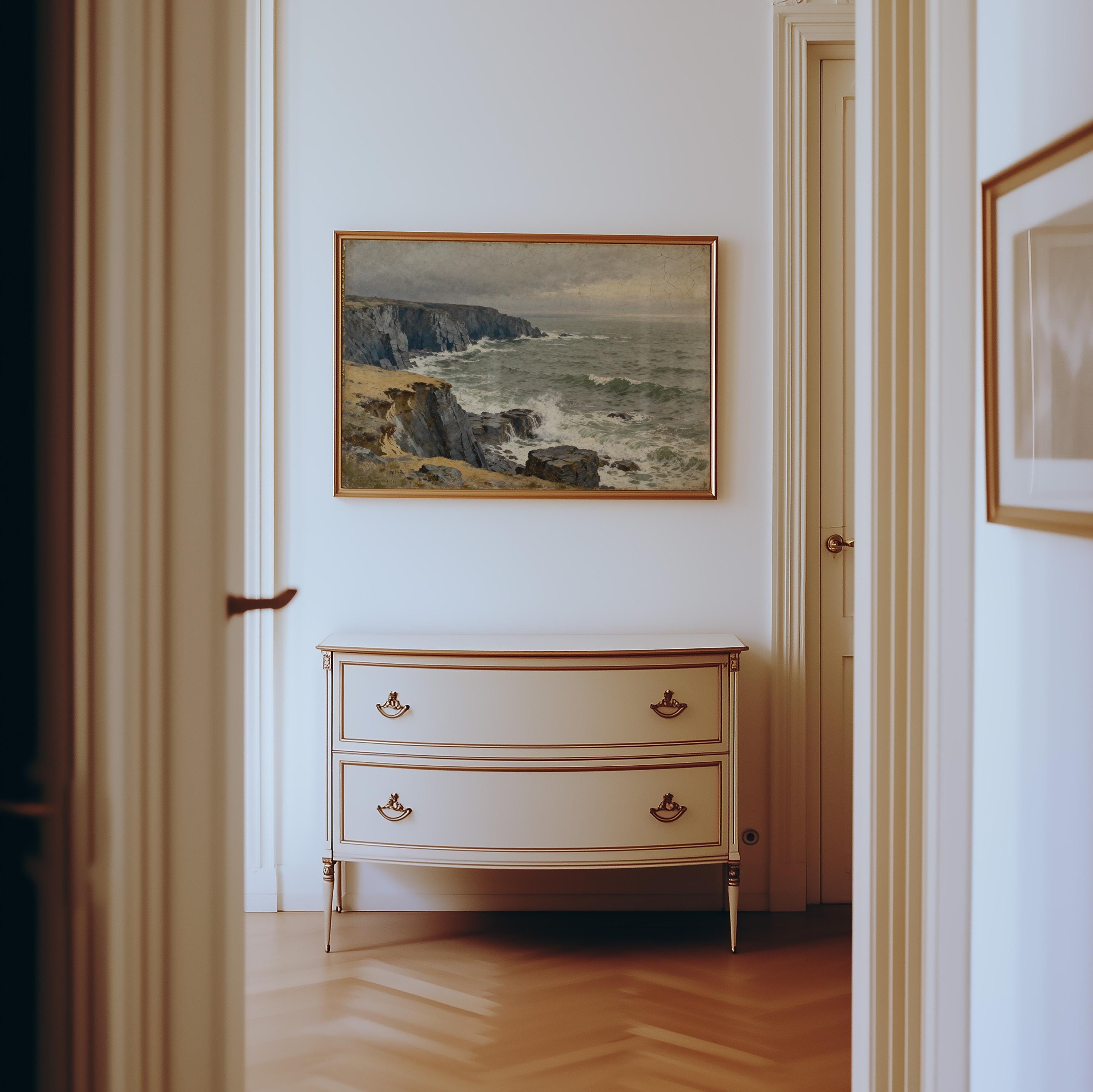 a hallway with a painting of a cliff overlooking the ocean hanging on the wall above a white dresser with two drawers.
