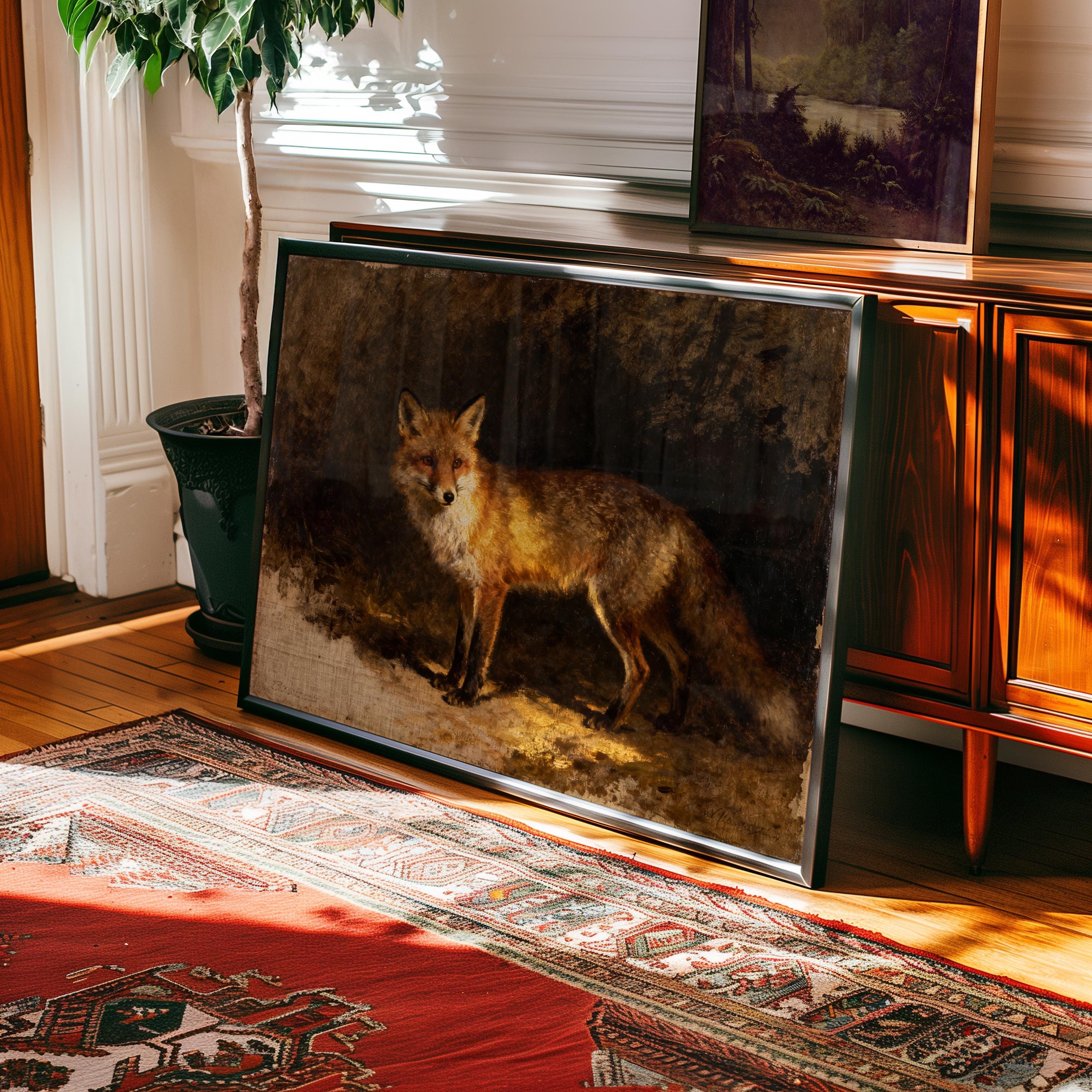 The Vintage Wildlife Art Print – Red Fox Wall Art, framed and leaning against a wooden console, brightens a sunlit room with a patterned rug, potted plant, and another landscape print displayed on the console.