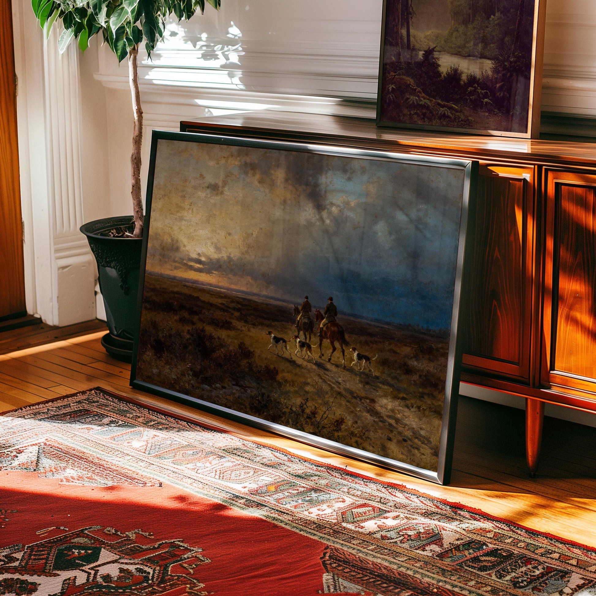 a large painting of a landscape with two people on horseback, set against a dramatic sky. The painting is framed and displayed on a wooden cabinet, with a rug on the floor in front of it.