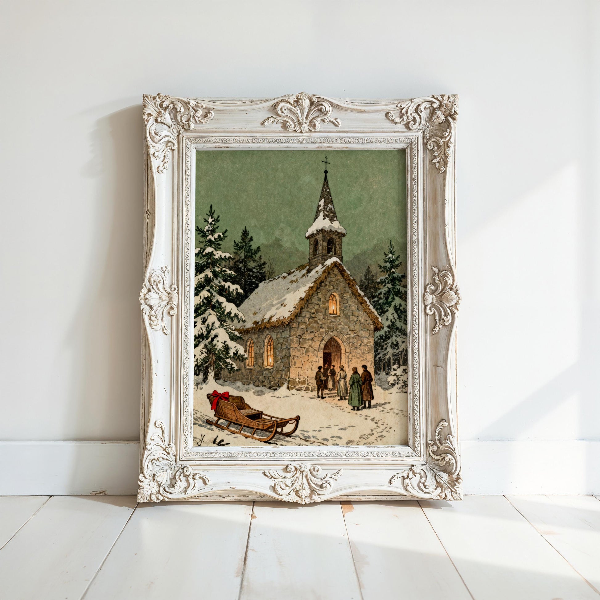 A white-framed painting depicting a snowy winter scene with a church, people, and a sled in the foreground.