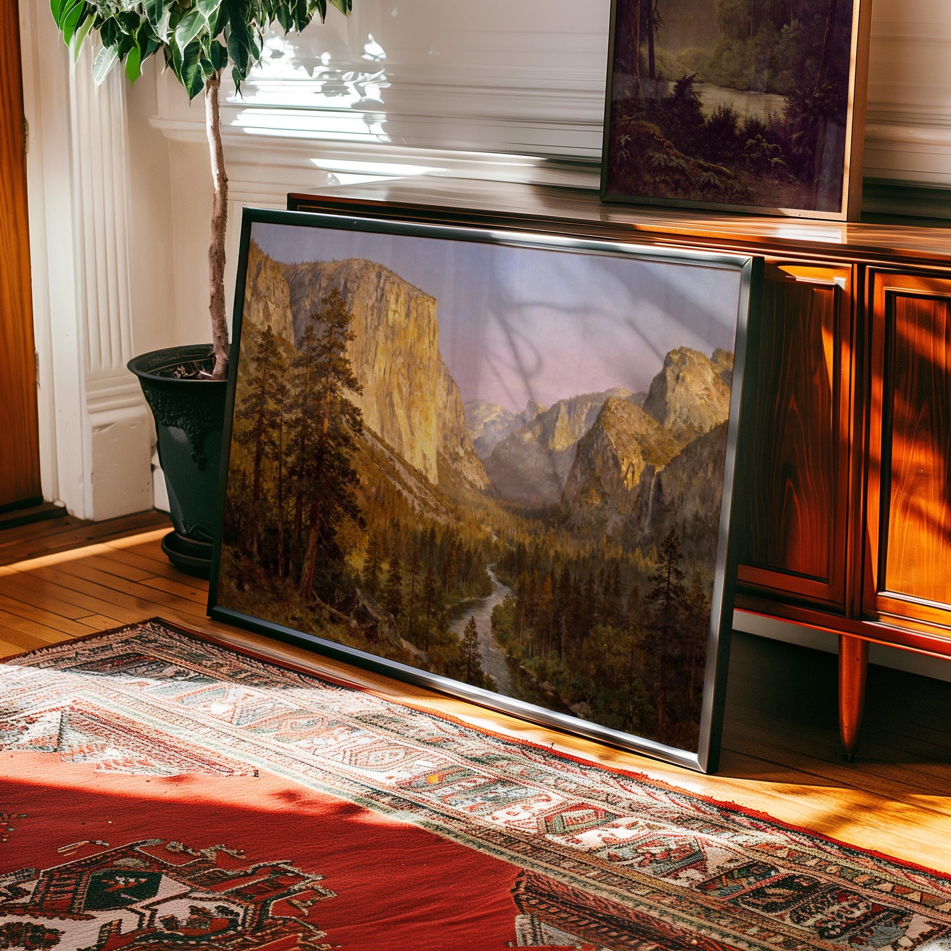 a large framed painting of a mountainous landscape, with a river winding through the valley. The painting is displayed on a wooden cabinet, and there is a rug on the floor in front of it.