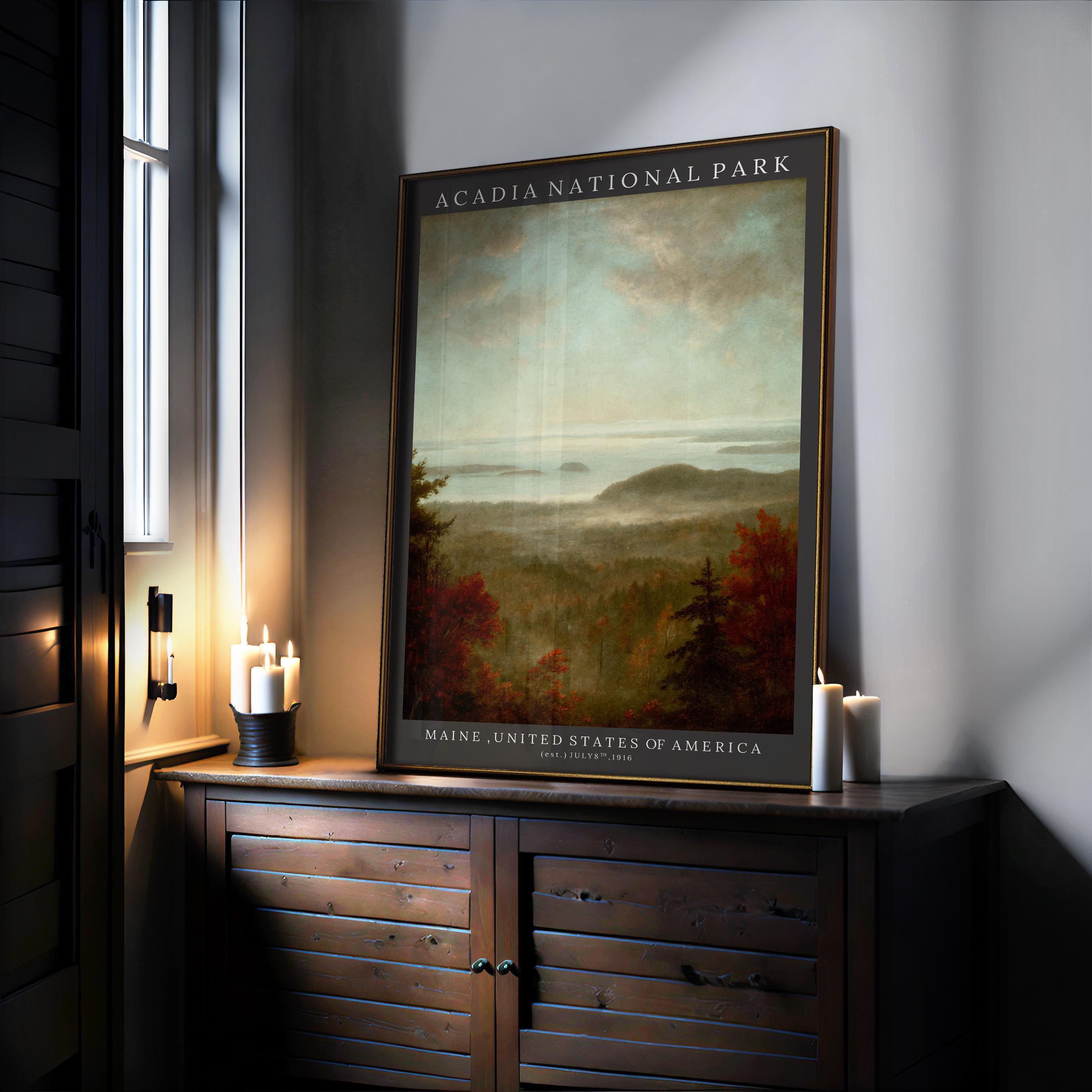 A framed Acadia National Park Poster – Vintage Botanical Coastal Print with Sand Beach Illustration sits on a wooden cabinet next to three lit candles, sunlight streaming in. The art print depicts a scenic landscape of trees and distant hills.