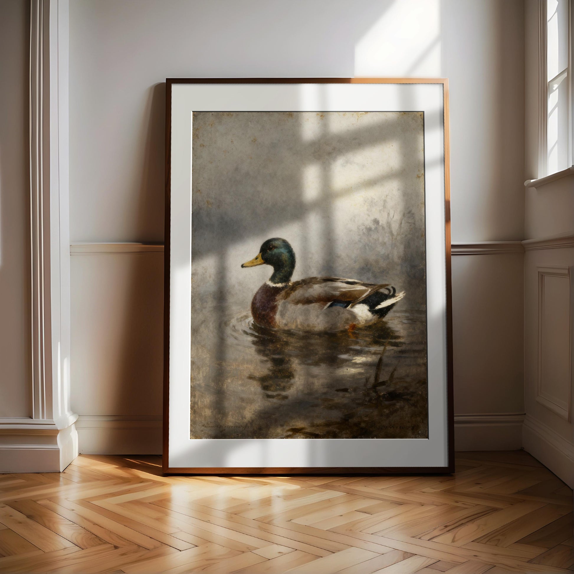 A framed painting of a duck swimming in a body of water is displayed on a wooden floor in a room with white walls.