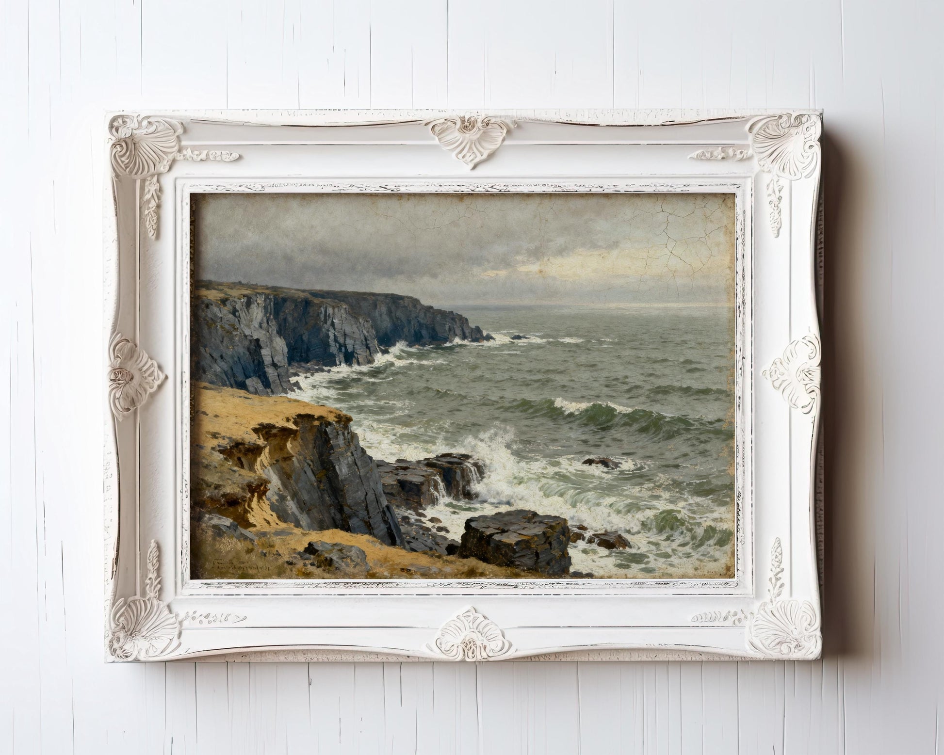 The image is a painting of a rocky coastline with crashing waves, displayed in a white ornate frame.