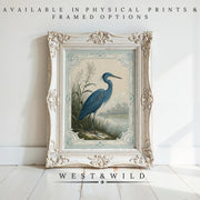 A framed archival print of a Great Blue Heron in William Morris style, displayed on a white wall with sunlight. "Available in physical prints & framed options" above; "West & Wild Art Archive" below. Great Blue Heron Print – Vintage Bird Wall Art.