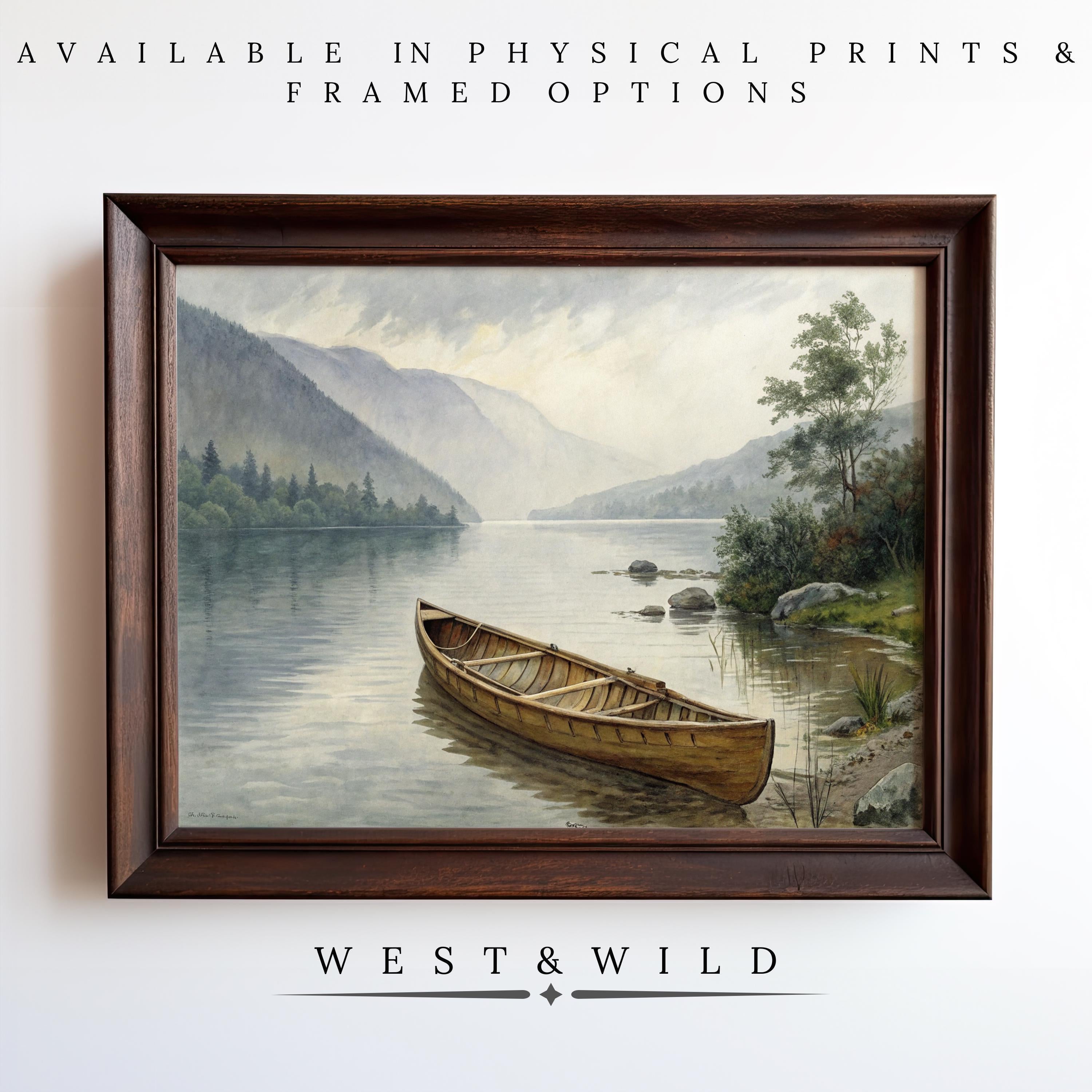 A framed Mountain Lake Oil Painting – Vintage Wall Art With Canoe hangs on a white wall, depicting a wooden canoe on a calm lake with mountains and trees. Available as prints or framed art. Below: West & Wild Art Archive.
