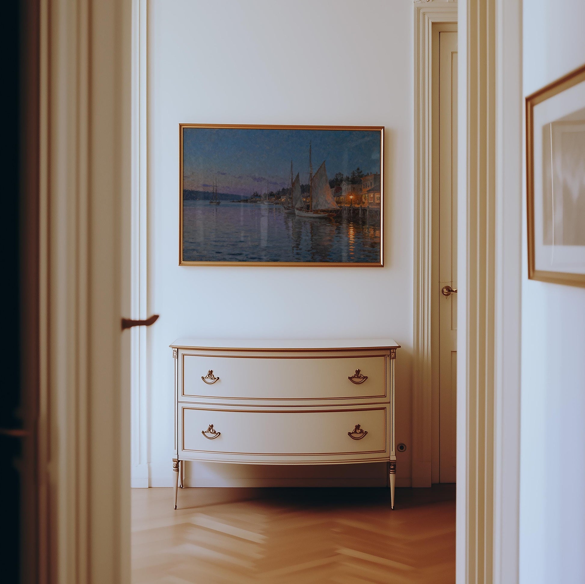 a hallway with a white dresser and a framed painting of a sailboat on the wall.