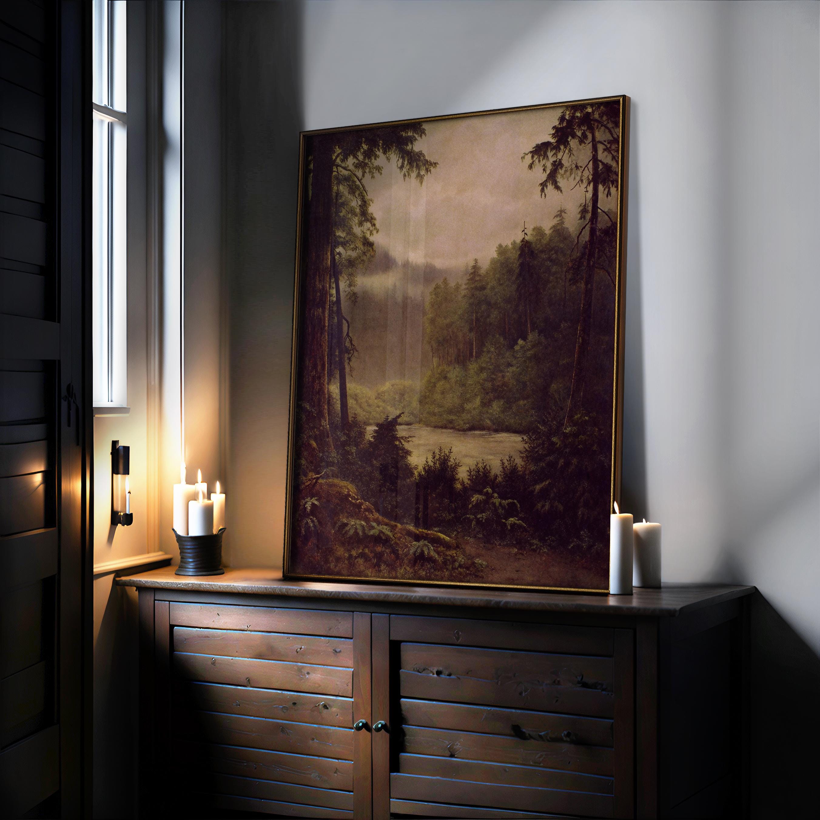 The Olympic National Park Print - Framed Rainforest Art | Vintage Forest Painting is displayed on a dark wooden cabinet, surrounded by glowing pillar candles with soft window light—ideal Pacific Northwest wall decor.