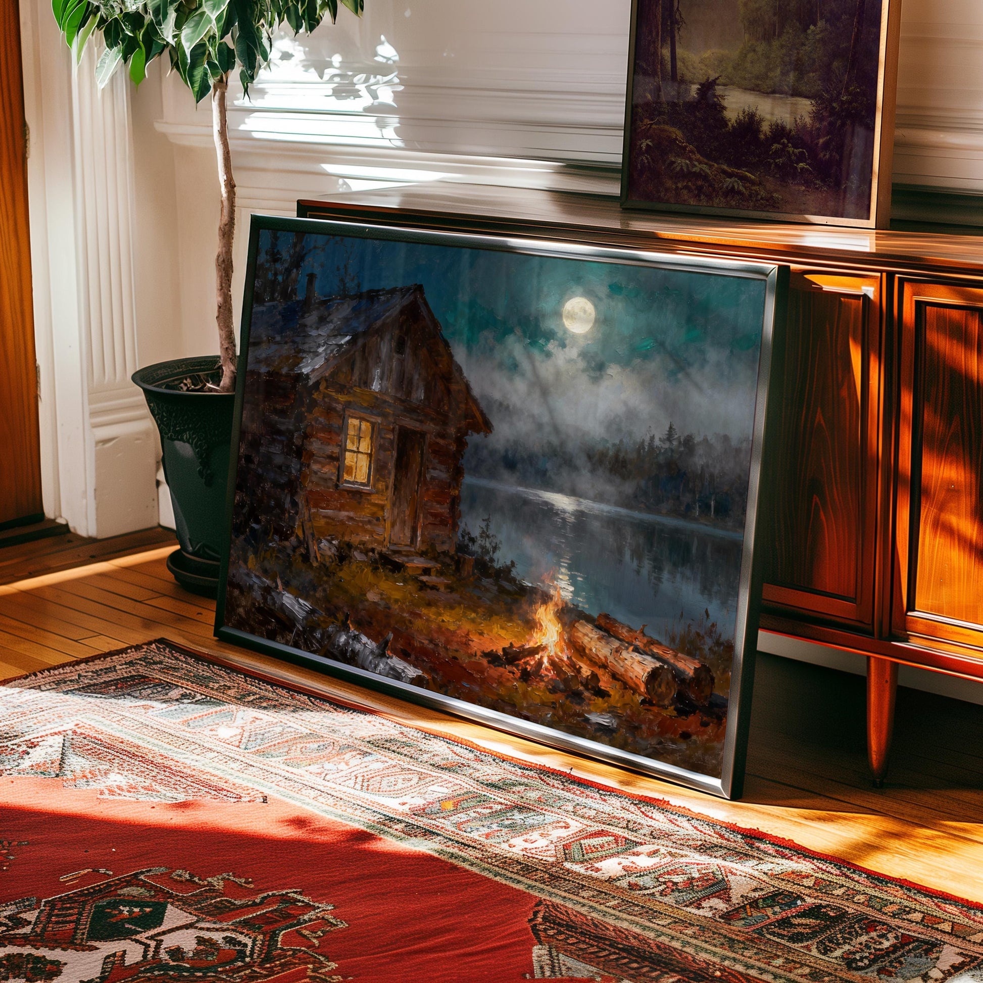 The Vintage Log Cabin Print – Rustic Cabin Art with Campfire Glow & Moonlit Lake adds warmth to any sunlit room, staying vibrant alongside the red rug and houseplant thanks to its archival quality.