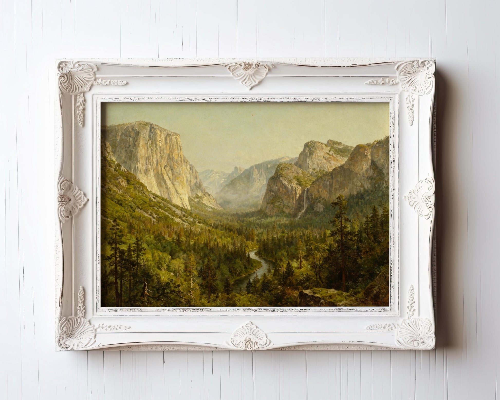 The Yosemite Valley Art Print – Classic American Landscape with River View, in an ornate white frame, displays a lush green valley with mountains, pine trees, and a winding river. Framed wall art from the West & Wild Art Archive. Archival quality vintage print.
