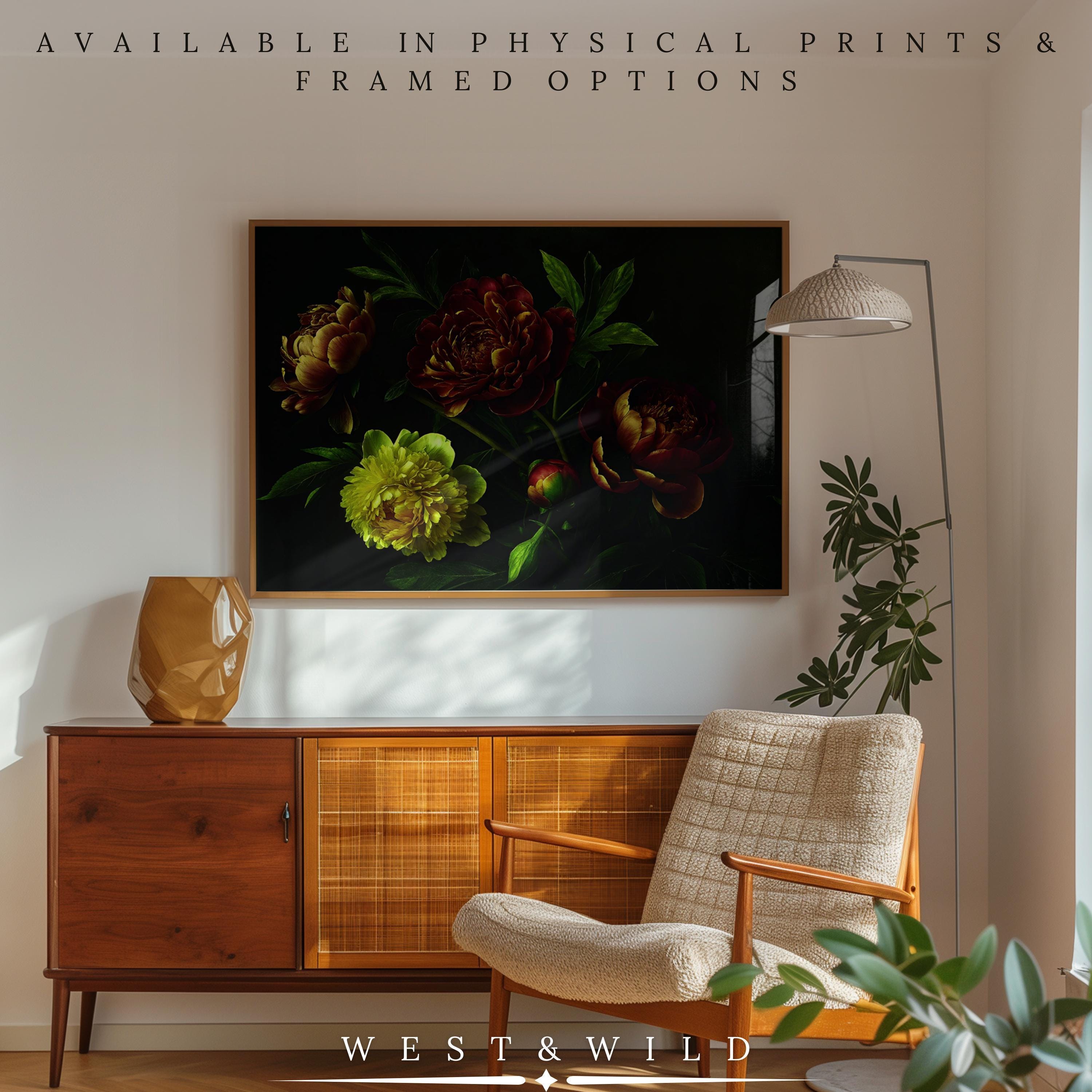 A cozy living room with a mid-century modern sideboard, armchair, floor lamp, and the Peony Wall Art – Framed Floral Art Print. Text: Available in archival quality prints & framed options. WEST&WILD.