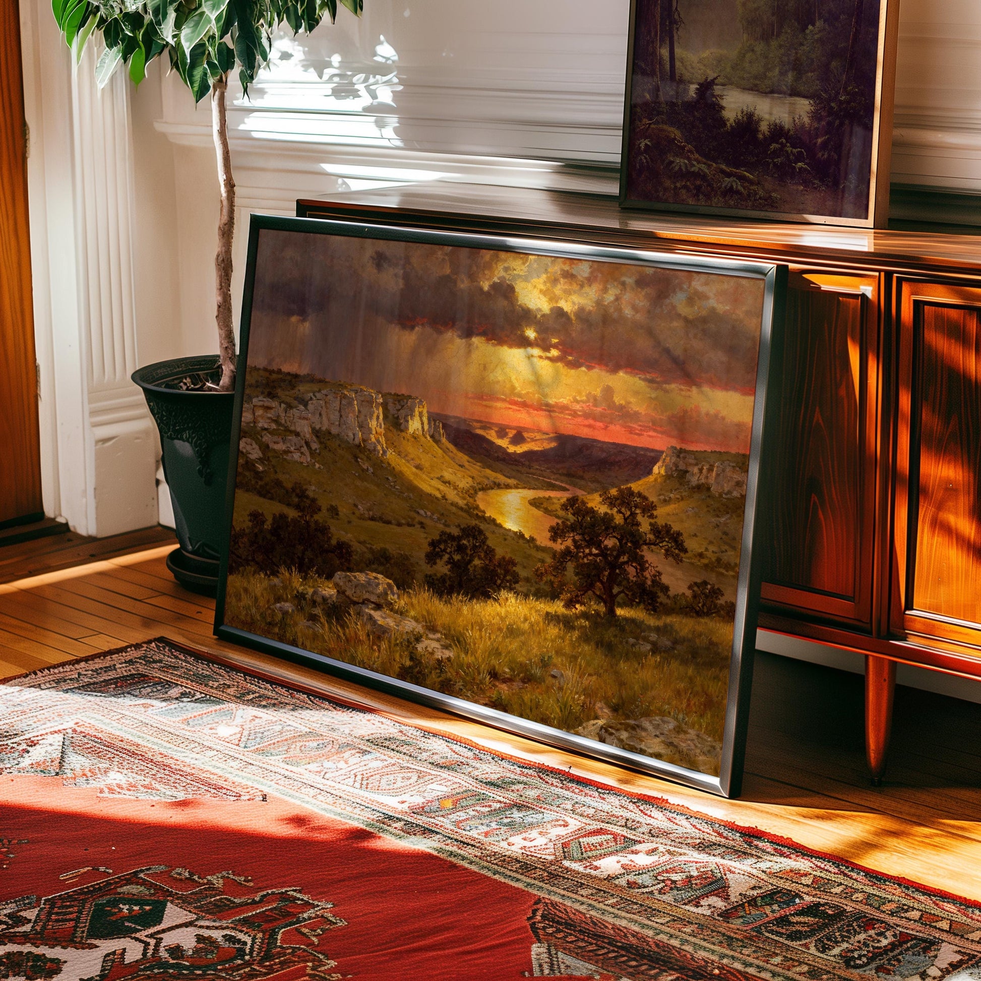 a large landscape painting hanging on a wall, depicting a scenic countryside with a river and mountains in the background.