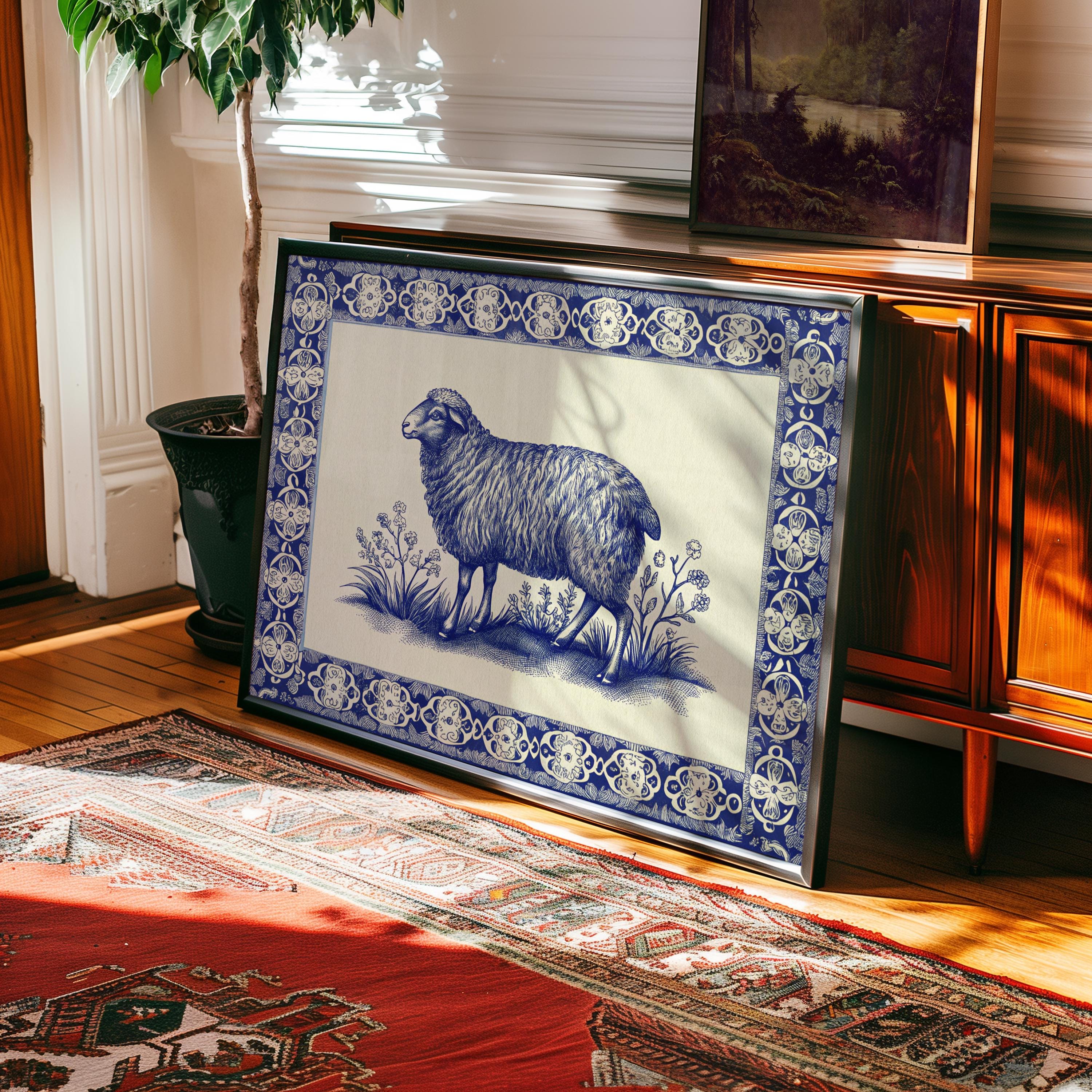 The Framed Sheep Print – Blue China Pattern Rustic Wall Art features a botanical blue sheep with a decorative border, displayed in a sunlit room near a wooden cabinet, potted plant, and patterned rug.