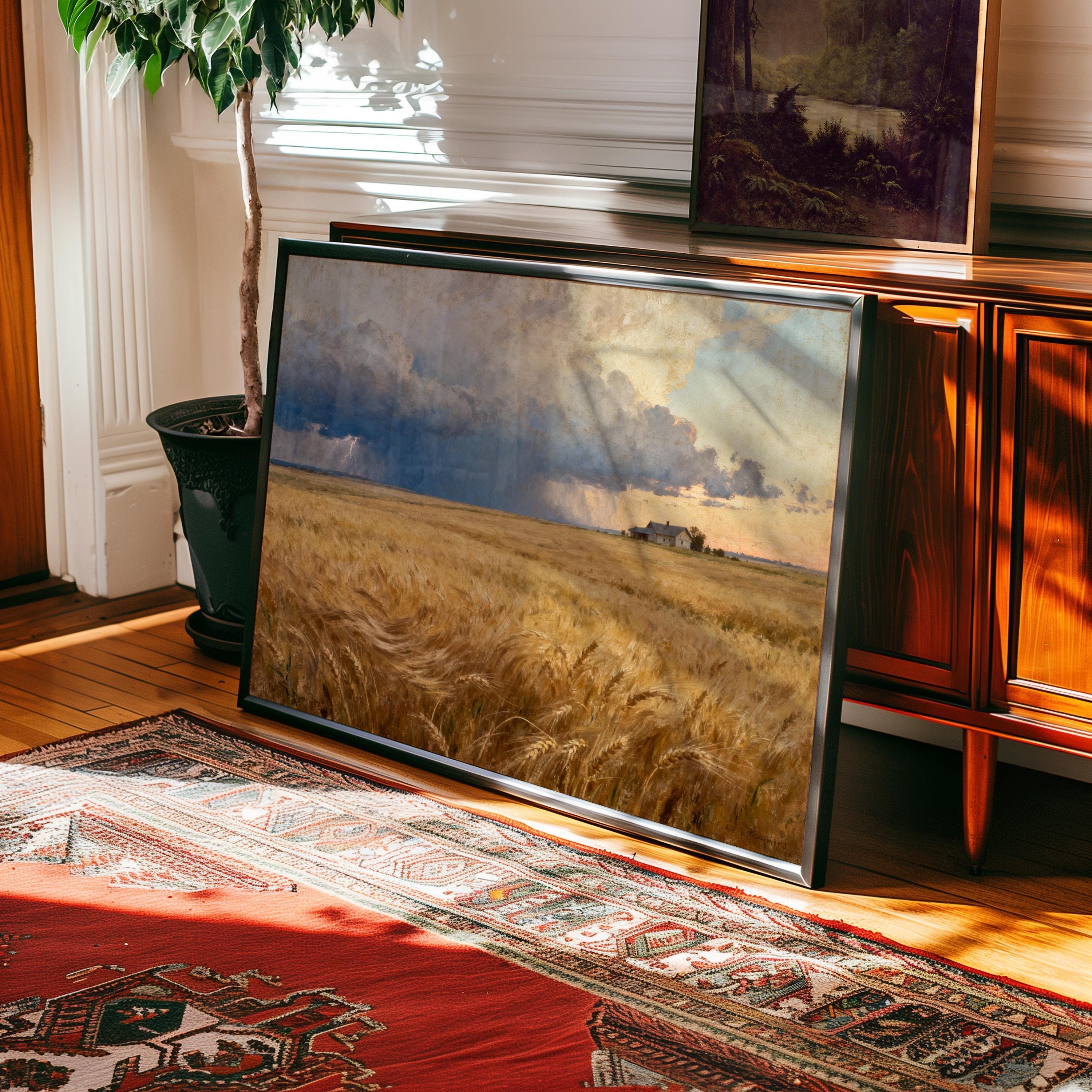 a large framed painting of a field with a cloudy sky in the background, placed on a rug in a room with wooden furniture.