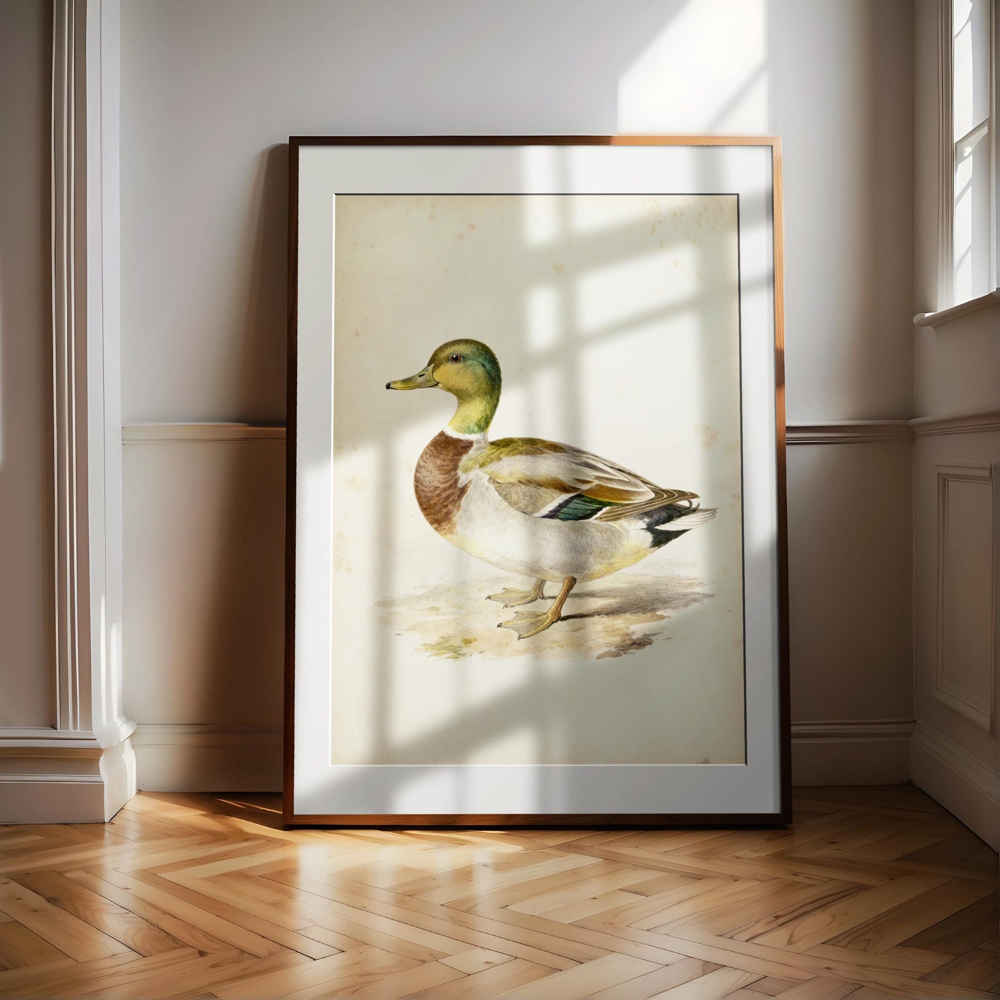 A framed painting of a duck is displayed on a wooden floor in a room with white walls.