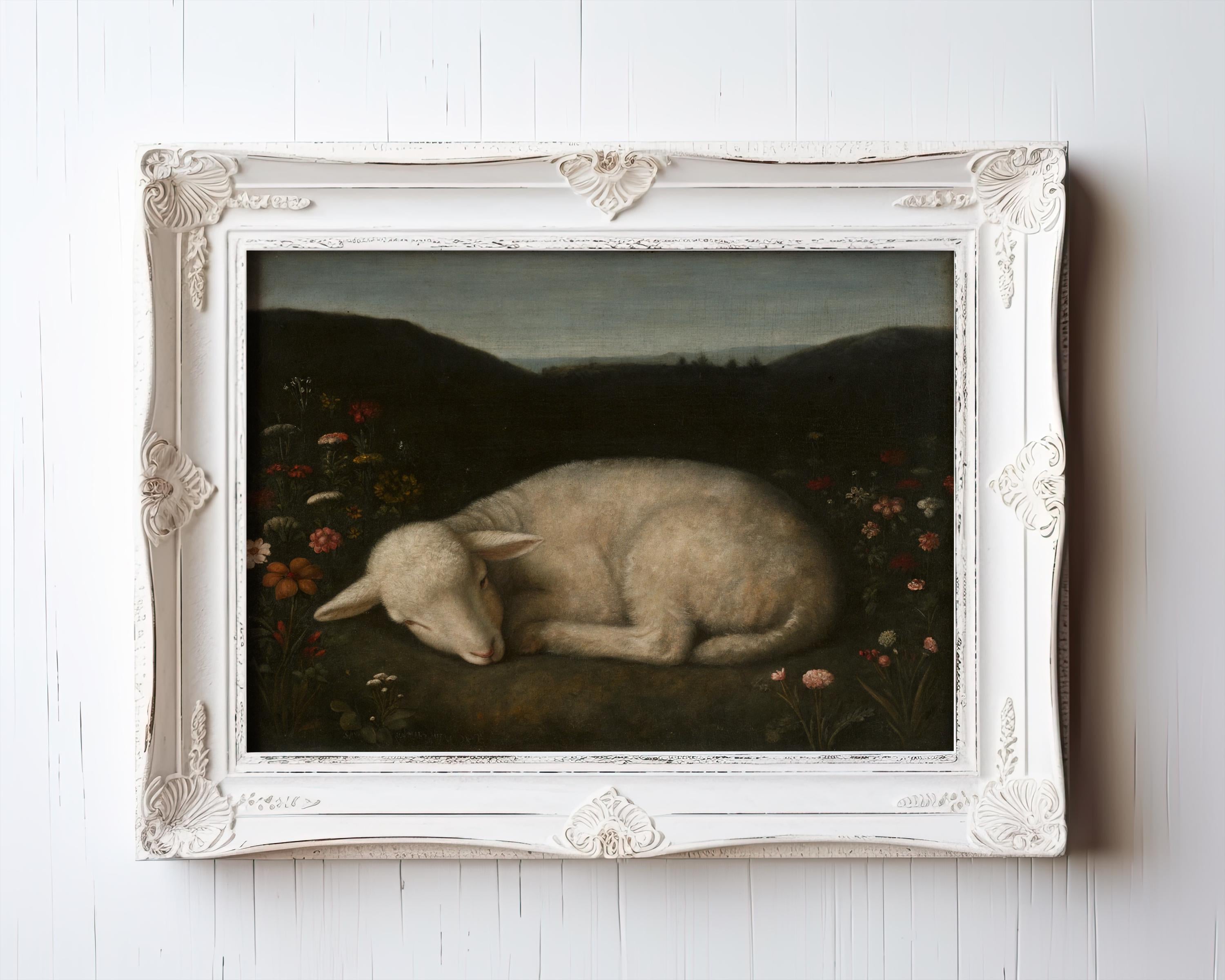The Vintage Lamb Art Print – Sleeping Lamb Nursery Art features a white lamb among flowers on grass with a dark mountain backdrop, framed in an ornate white frame for rustic cottage wall decor.