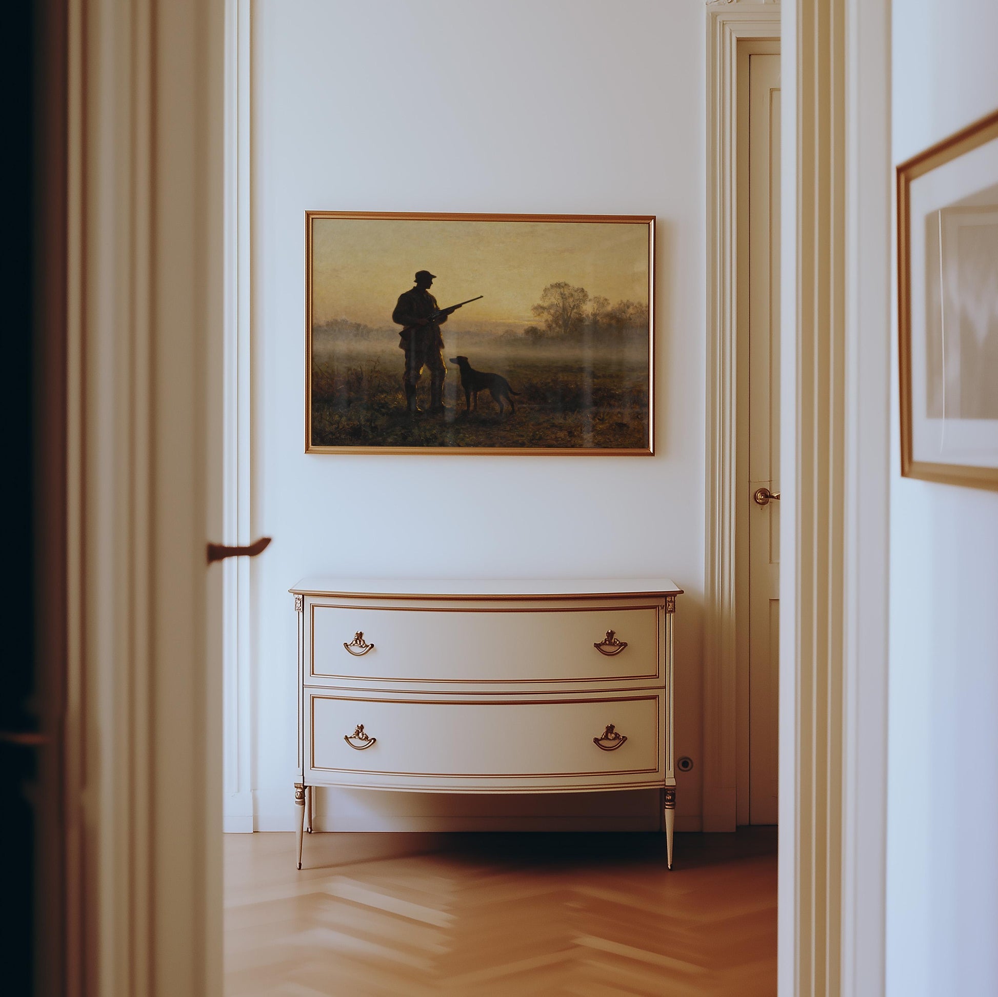 a hallway with a white dresser and a framed painting of a man with a dog on the wall.