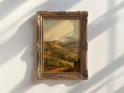 a painting of a countryside landscape, hanging on a white wall.