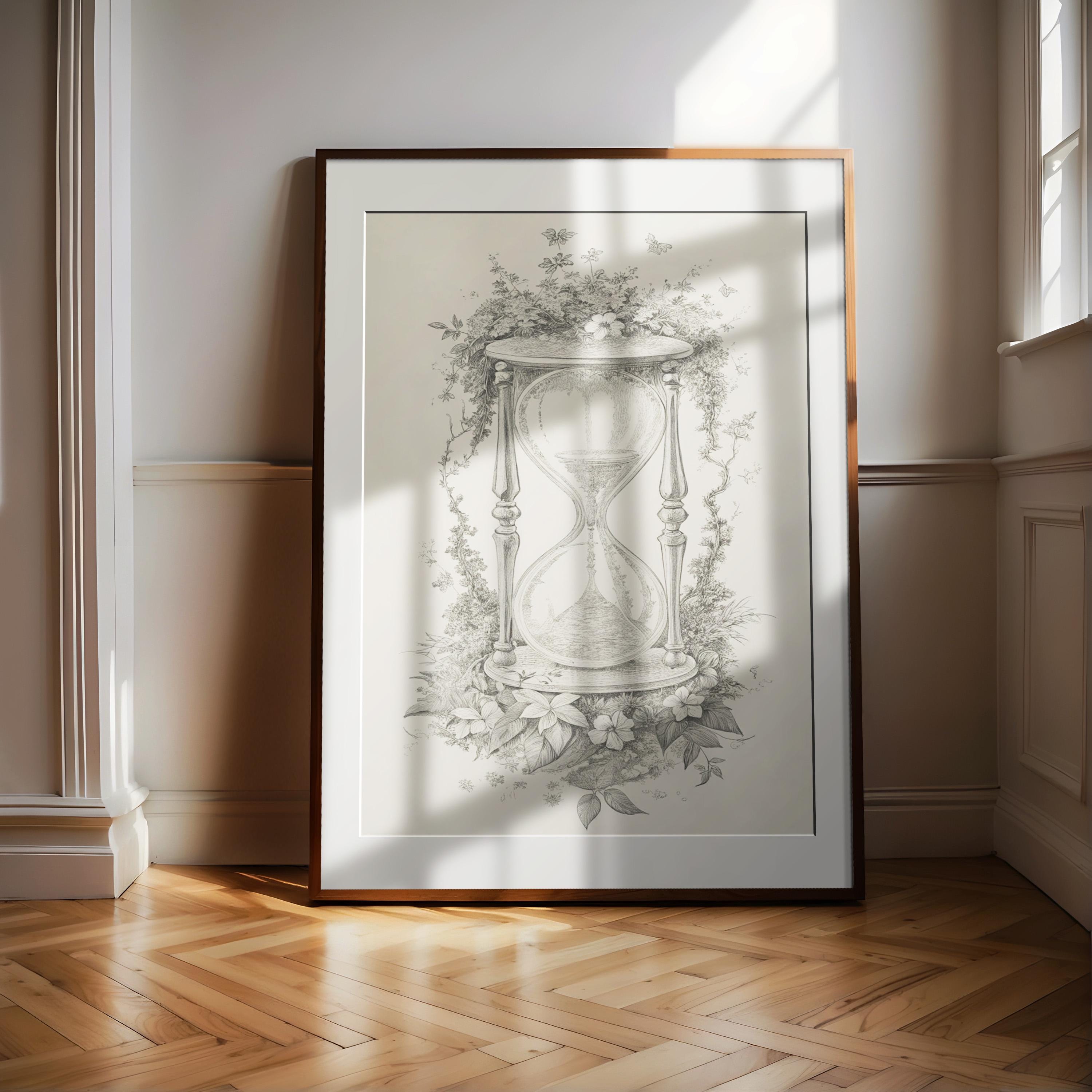A framed illustration of an hourglass is displayed on a wooden floor in a room with white walls.