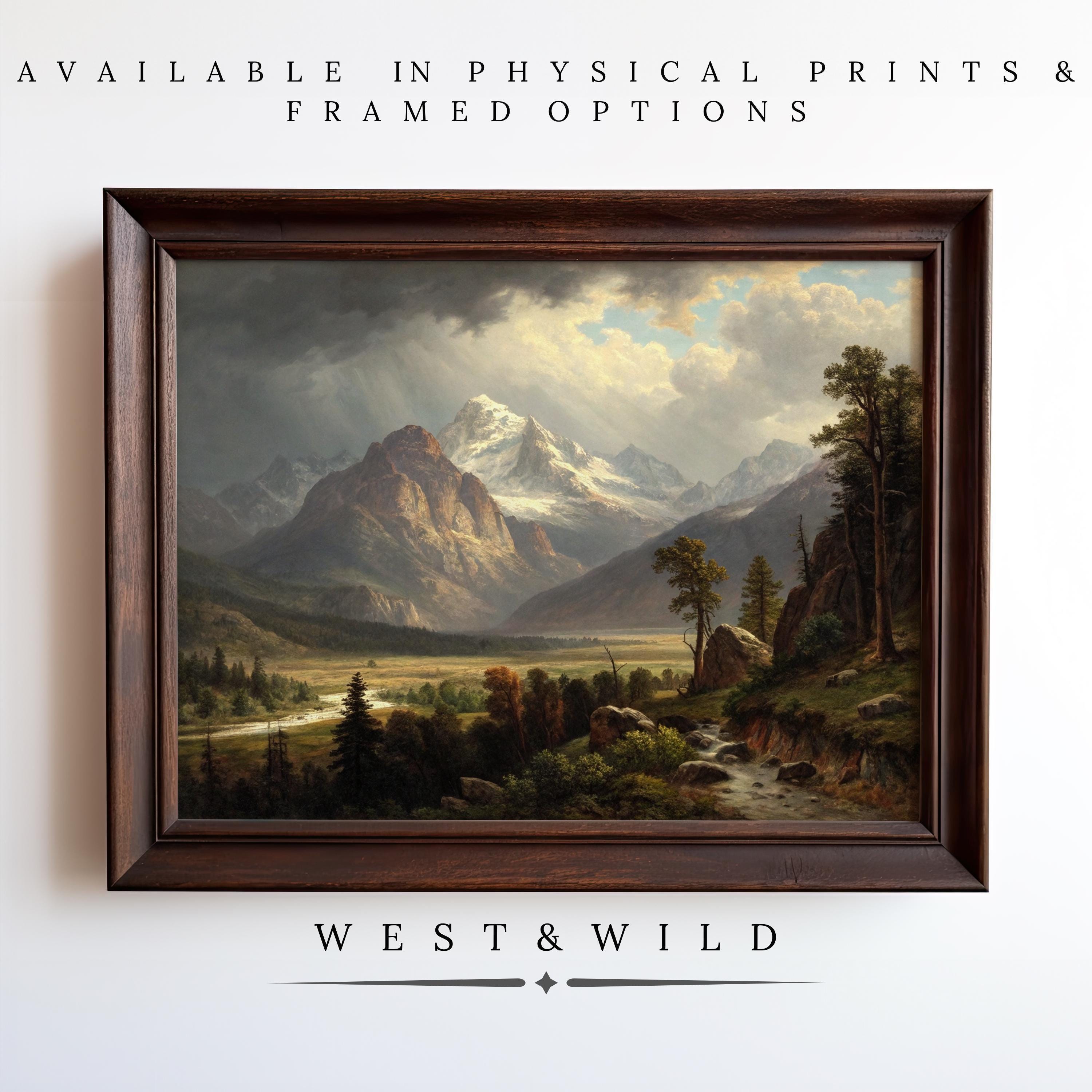 A Mountain Oil Painting featuring a rustic framed mountain range hangs on a white wall. Text above reads: Available in Vintage Art Print & archival quality options. Below is the brand, West & Wild.