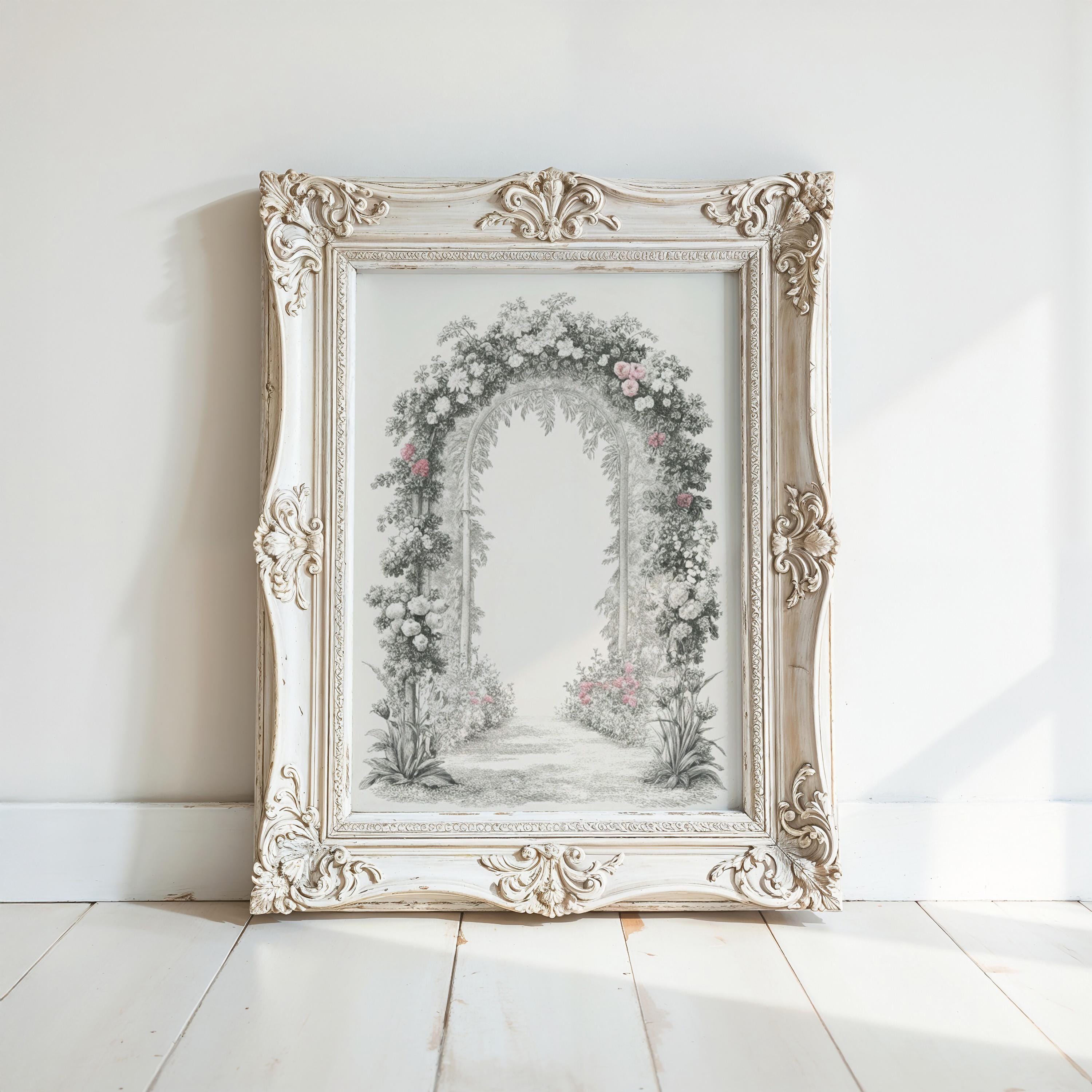 A white ornate frame with a floral arch is displayed on a white wooden floor against a white wall.