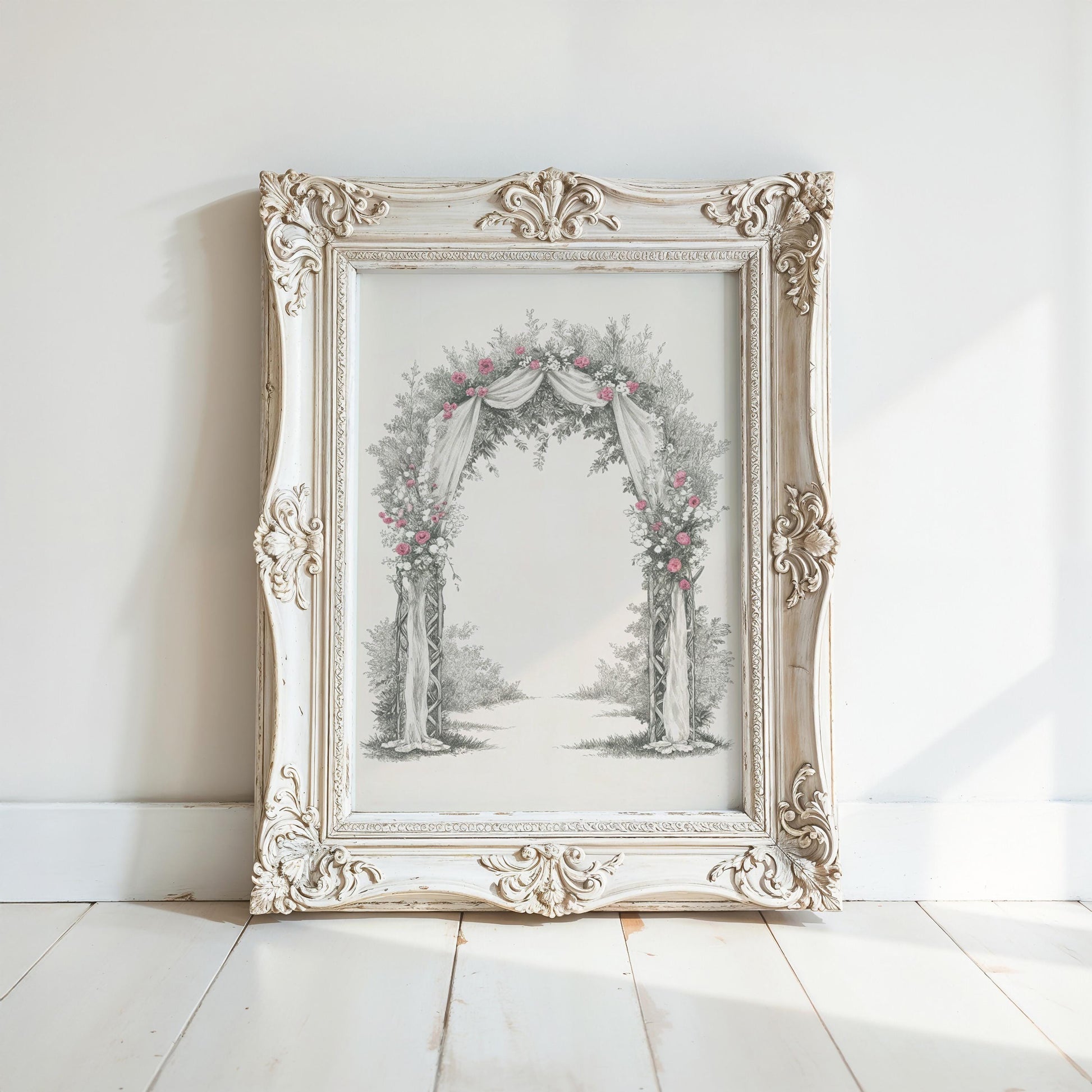 A white ornate frame with a floral arch design is displayed on a white wooden floor against a white wall.