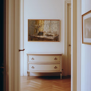 a hallway with a white dresser and a framed painting hanging on the wall above it.