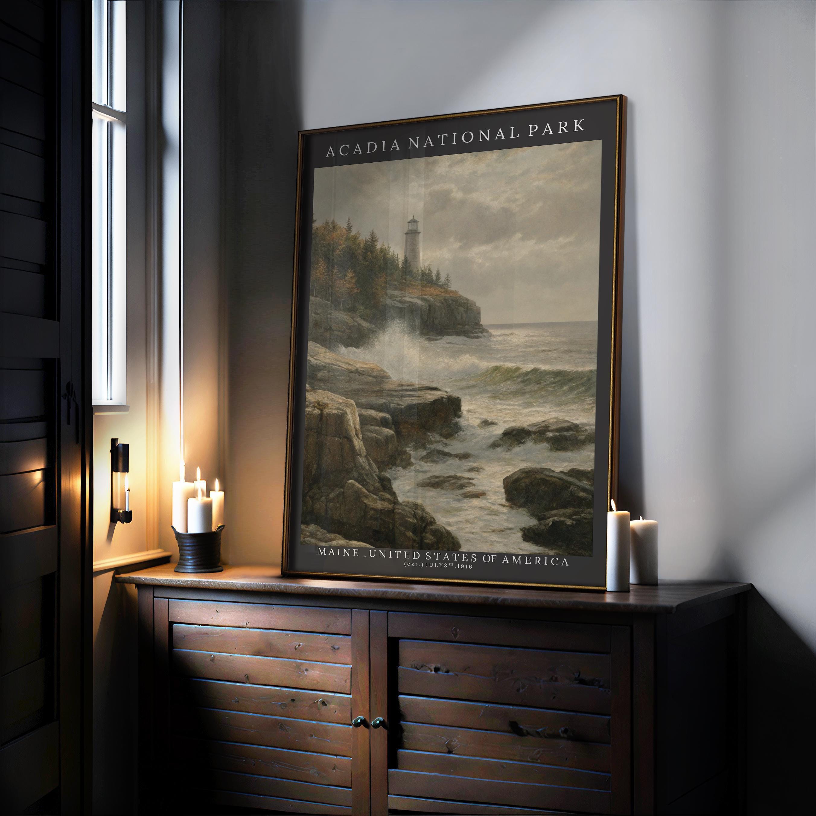 A framed Acadia National Park Poster—Vintage Otter Cliffs Illustration with coastal pines—rests on a wooden cabinet by lit candles and a sunlit window.