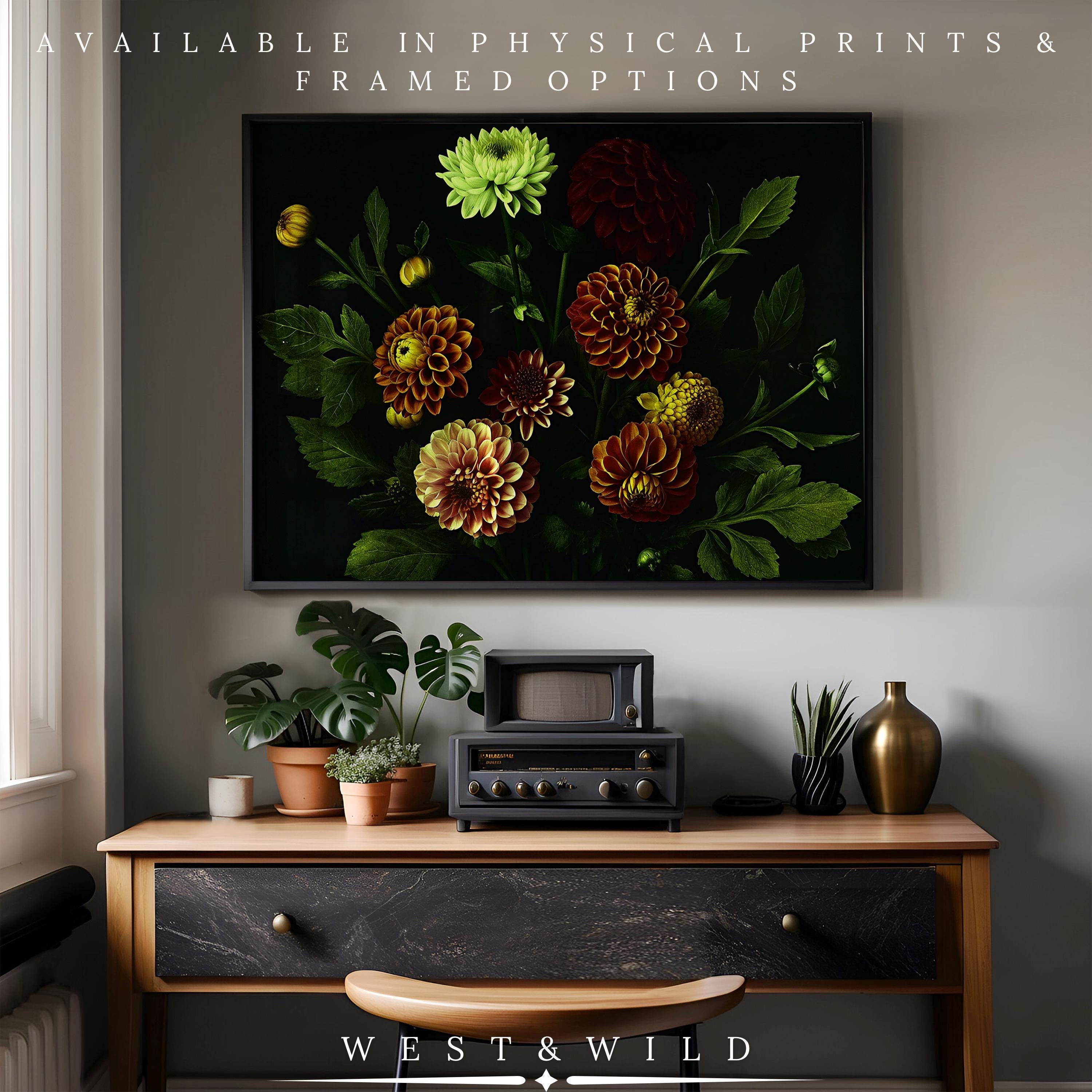 A modern living room features a wooden table, vintage radio, and plants. Above hangs the Dahlia Flower Print—vibrant botanical wall art with red and yellow blooms on a dark background. Available as prints or framed. WEST & WILD.
