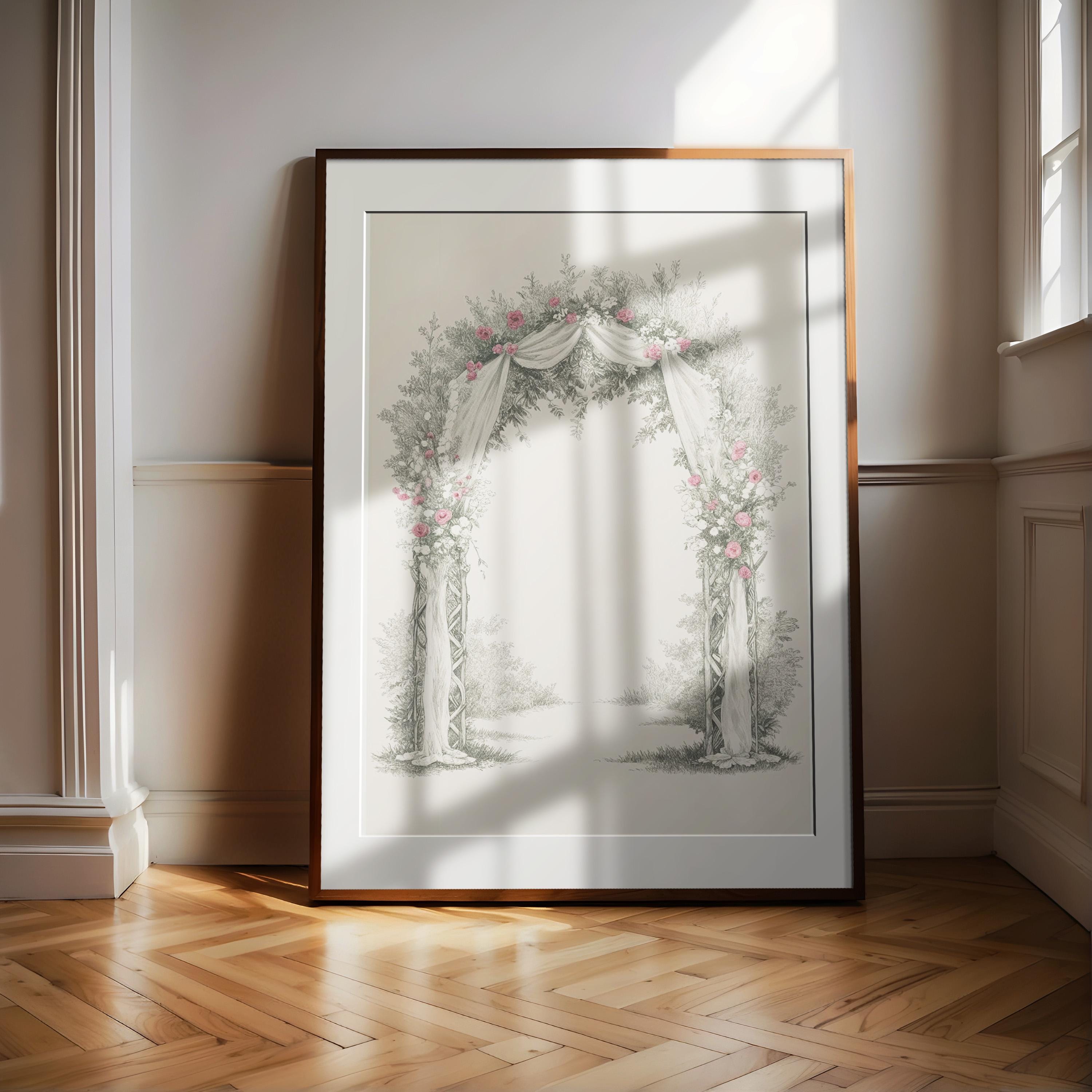 A large framed picture of an archway with flowers and greenery is displayed on a wooden floor against a white wall.