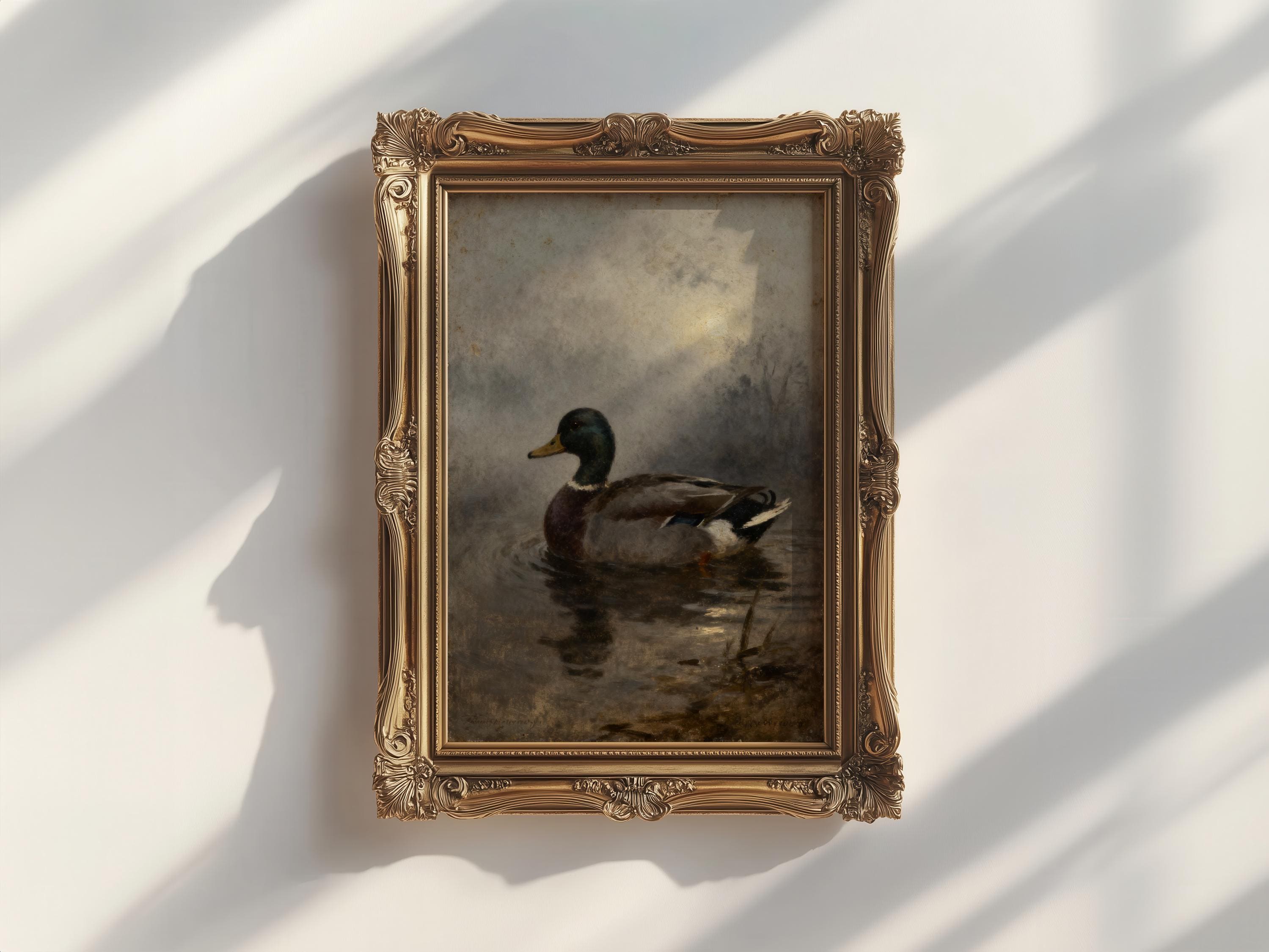 a painting of a duck swimming in a body of water, displayed in an ornate gold frame on a white wall.